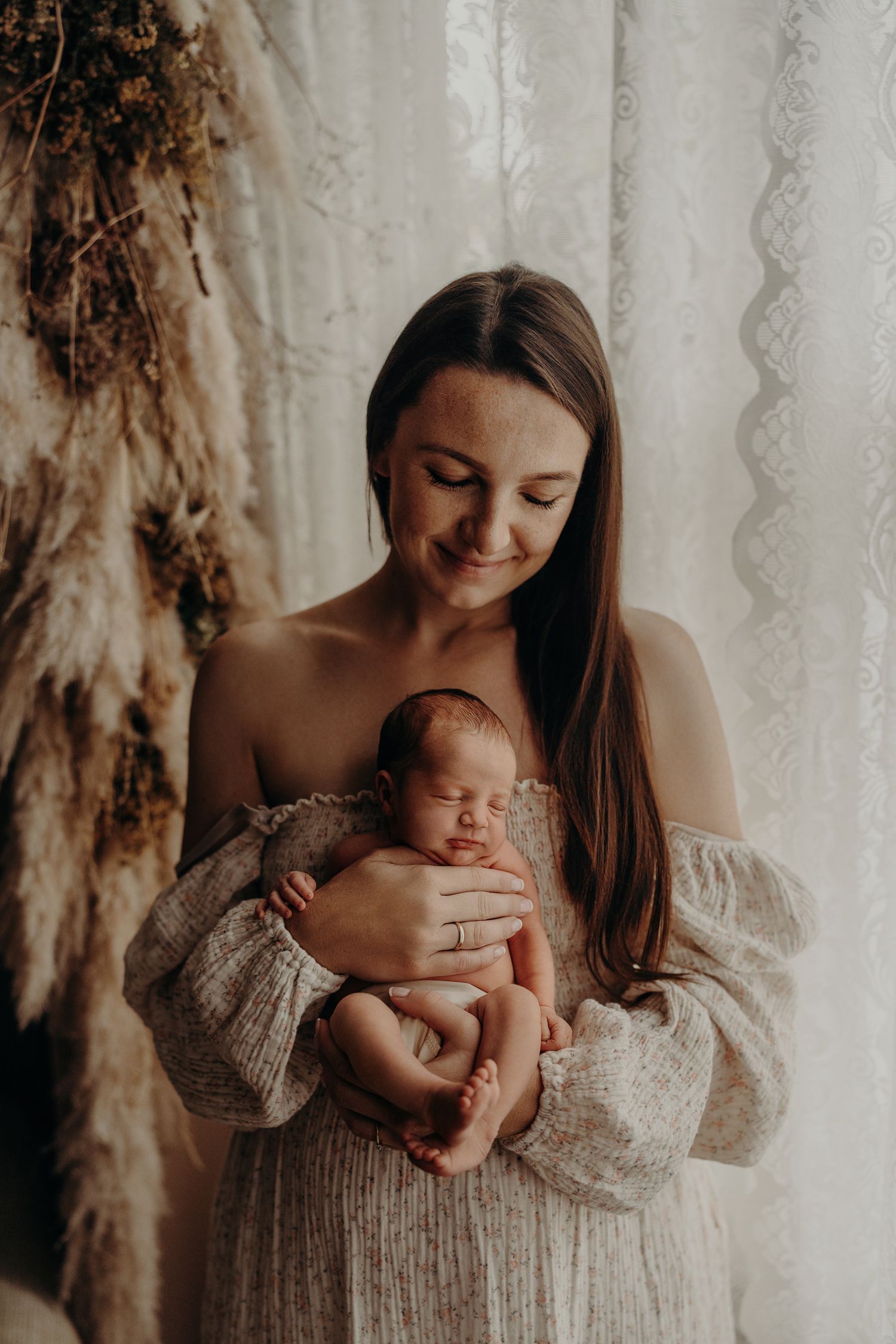 Artistic newborn photography with baby in cream-colored knit dress.