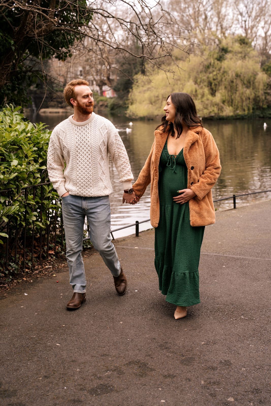 A man and a woman walking together on a path surrounded by trees and greenery.