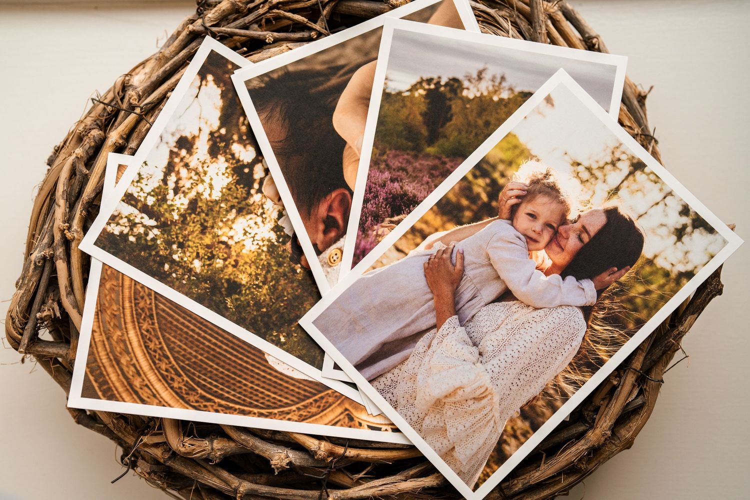 Collection of printed photographs arranged in nest-like display with natural elements.