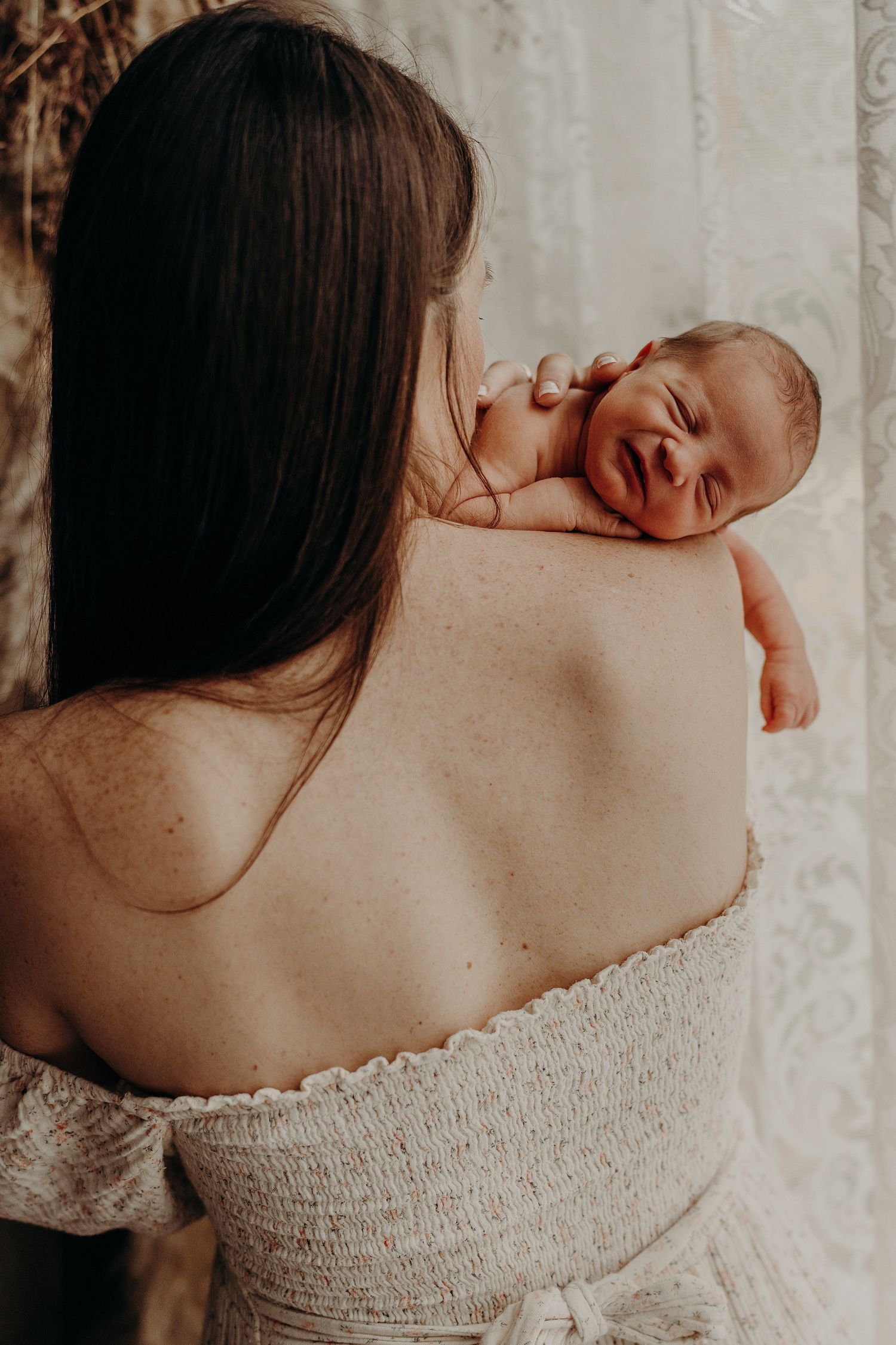 Tender moment captured during a newborn photo session with soft natural lighting.