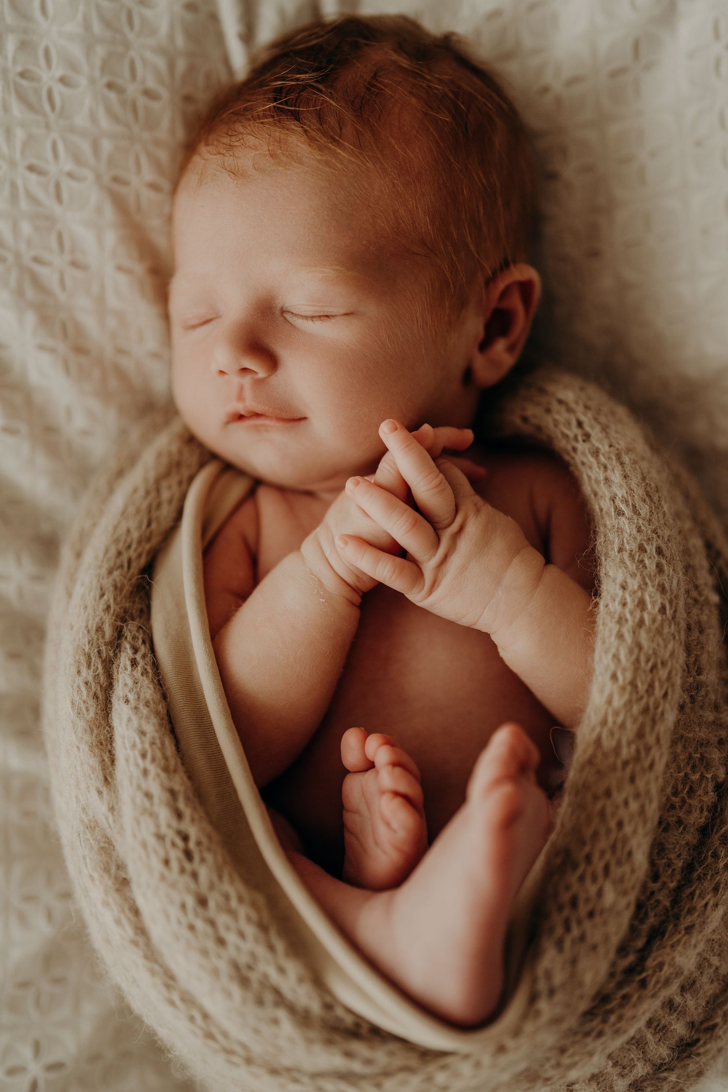 Peaceful newborn baby sleeping while wrapped in a cozy knit blanket.