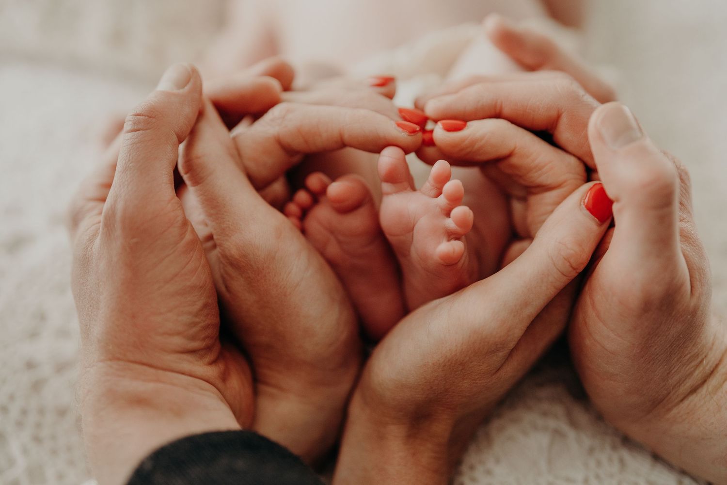 Close-up of tiny baby feet being held by loving hands.