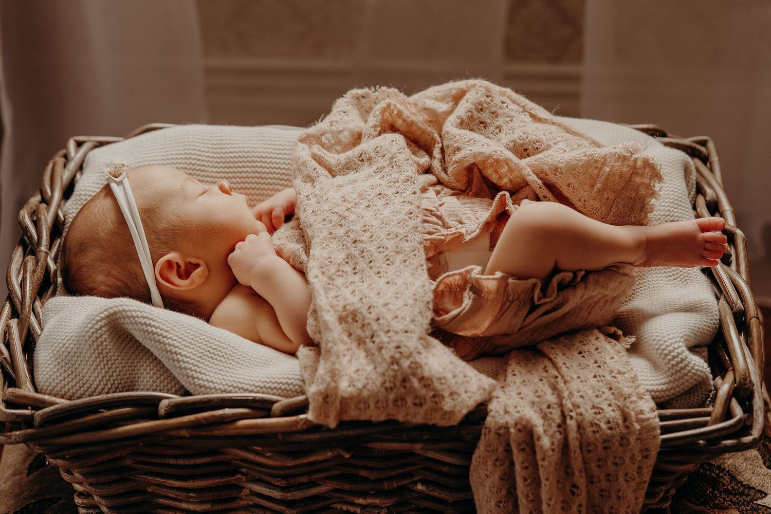Peaceful sleeping newborn nestled in a woven basket with soft textiles.