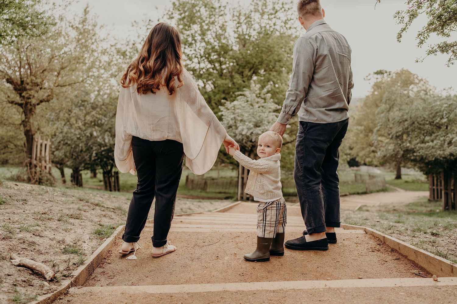 Family walking together on a dirt path through a peaceful park.