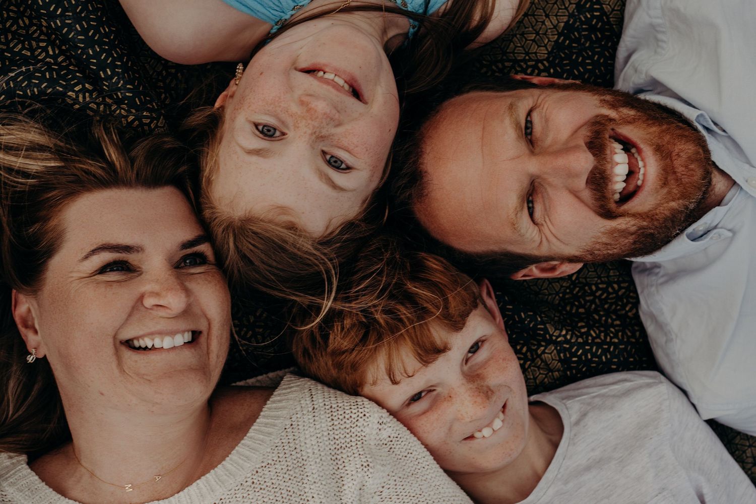 Close-up shot of family members laying down together with joyful expressions.