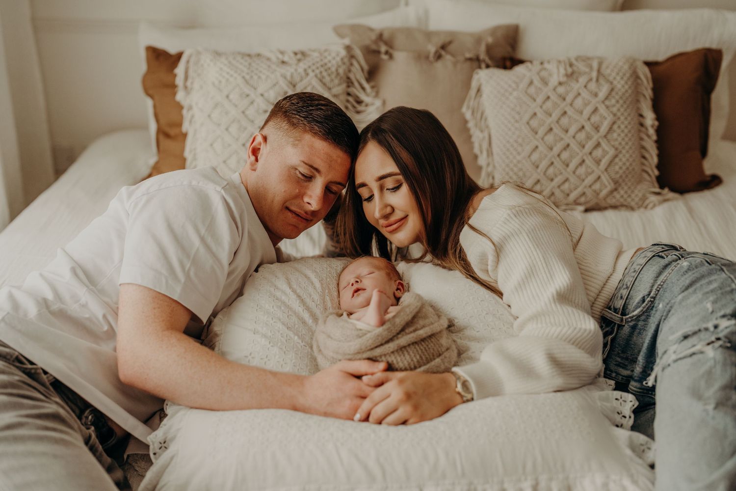 Family moment captured on white bedding with soft, natural window light.