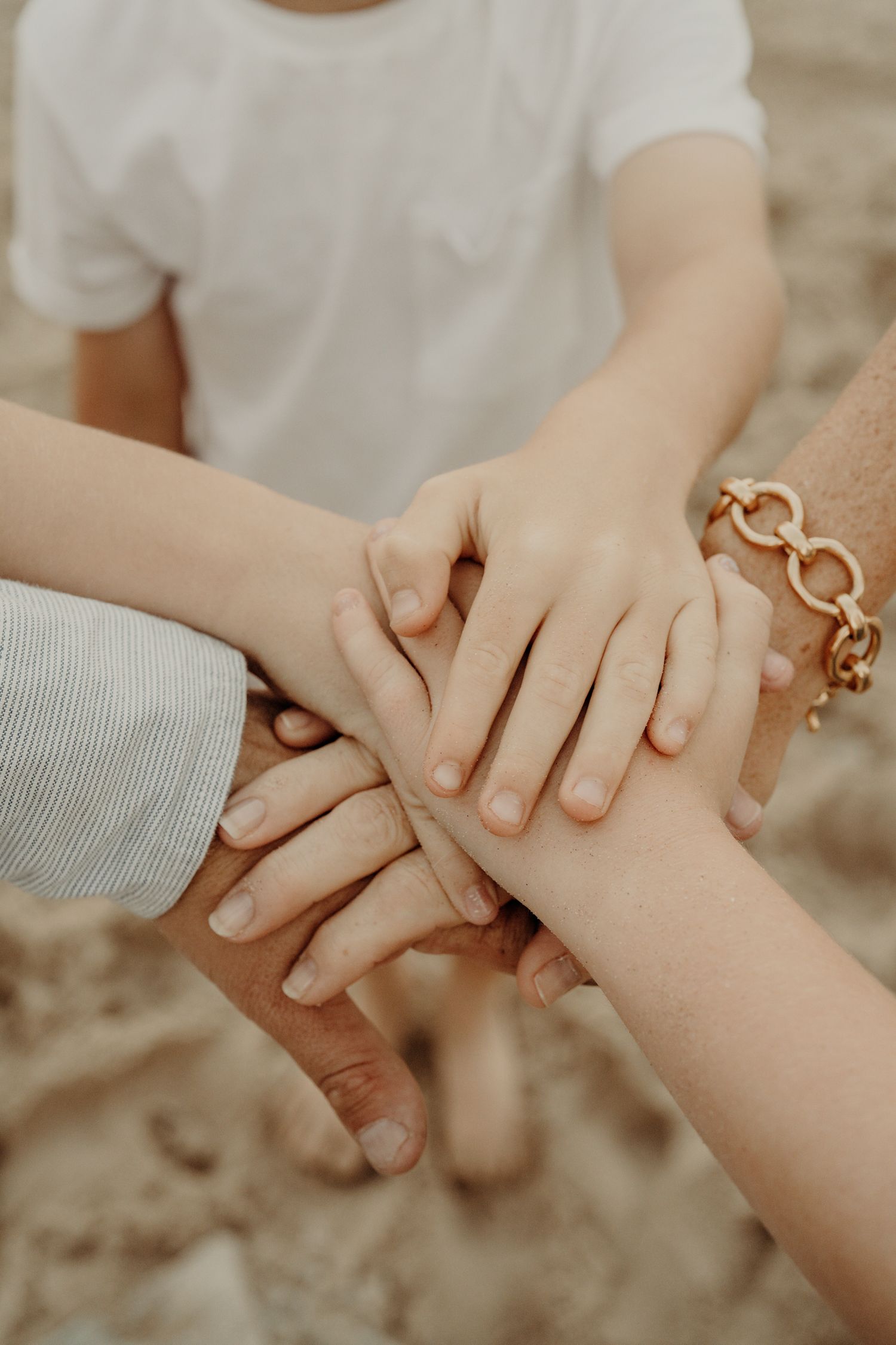 Close-up of hands gently holding each other in warm natural light.