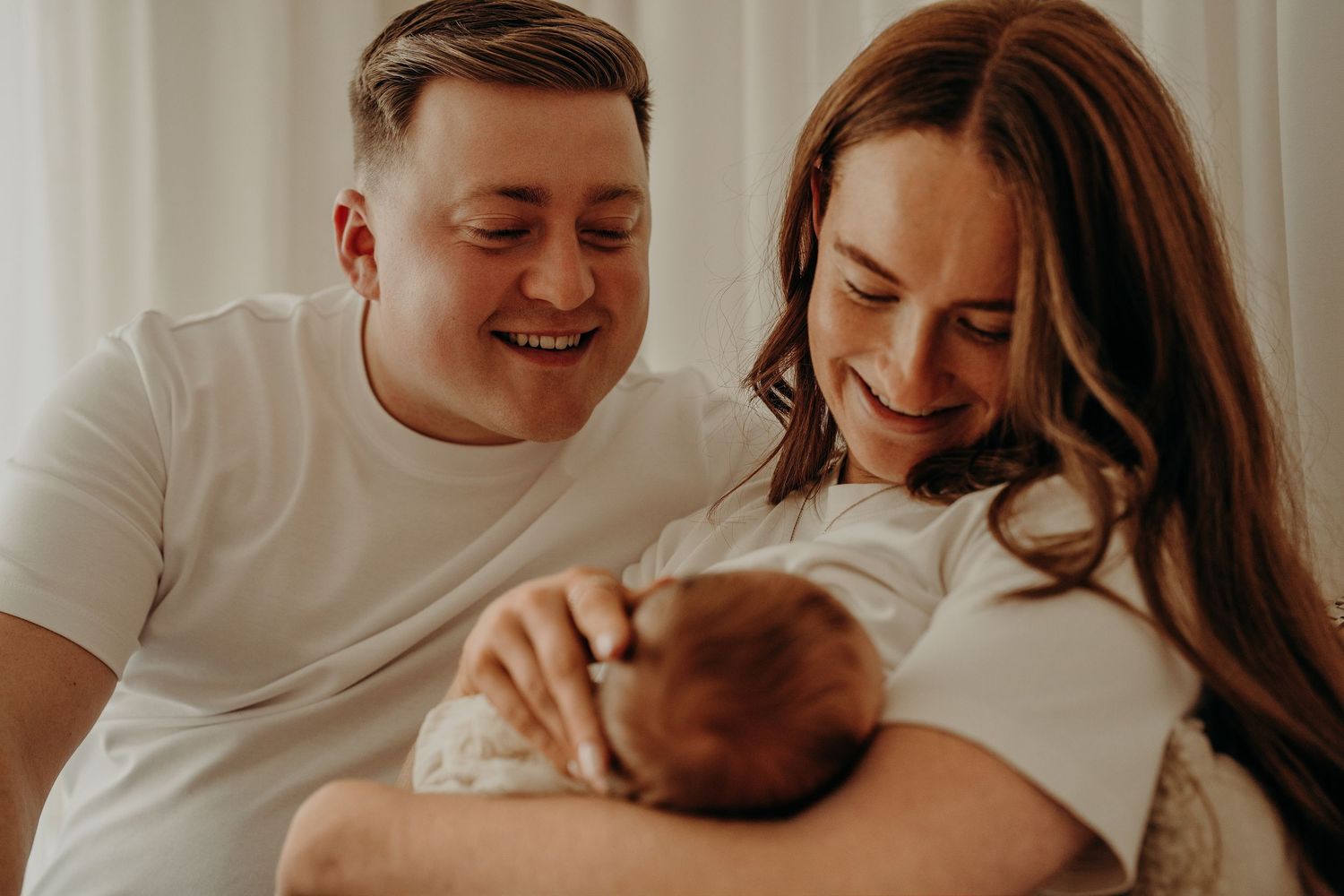 Intimate lifestyle newborn photography session showing tender family moments in soft natural lighting.