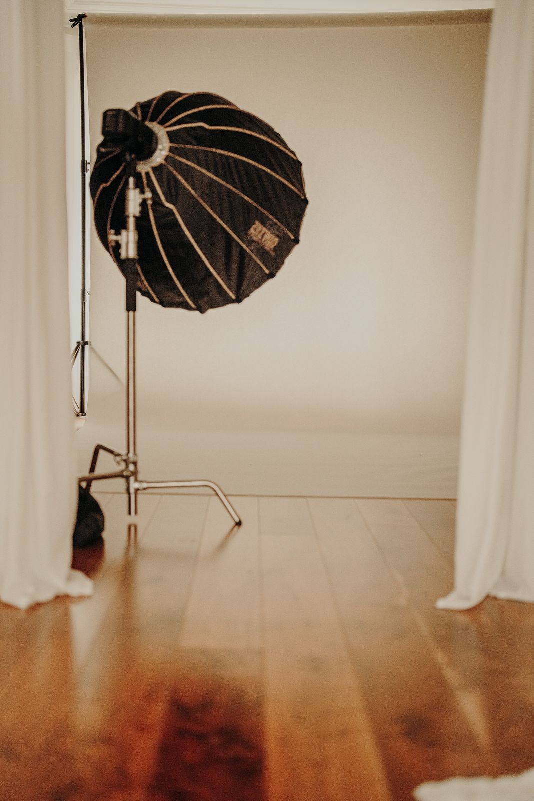 Photography studio setup with black umbrella light against wooden floor.