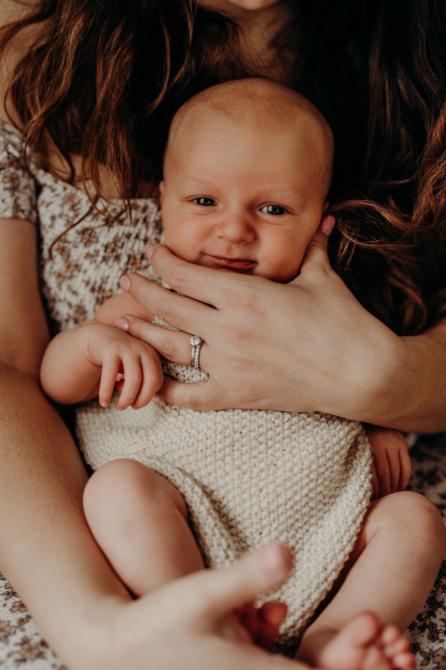 Happy baby in knit outfit smiling while being held.
