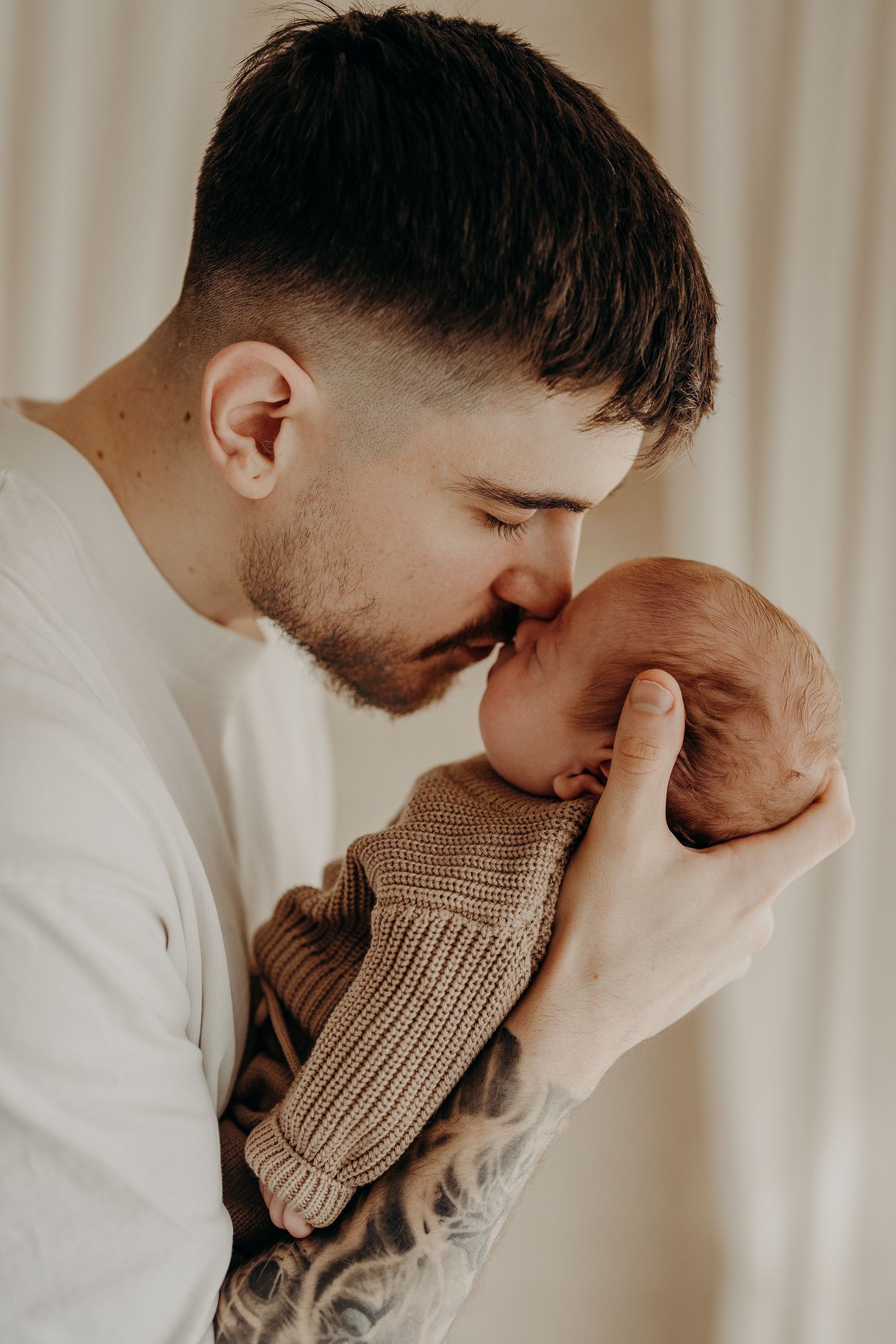 Parents sharing a nose-to-nose cuddle with newborn in natural light lifestyle studio session Dublin