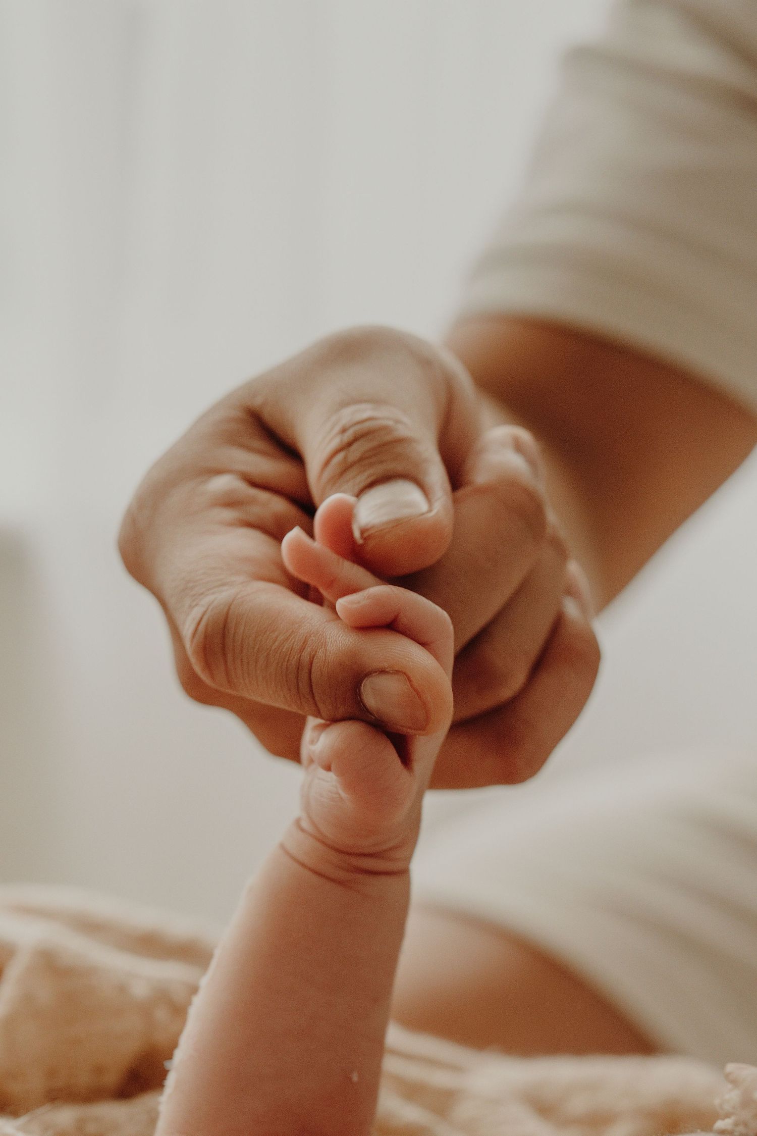 Close-up shots of a tiny baby's hand reaching out in soft natural light.