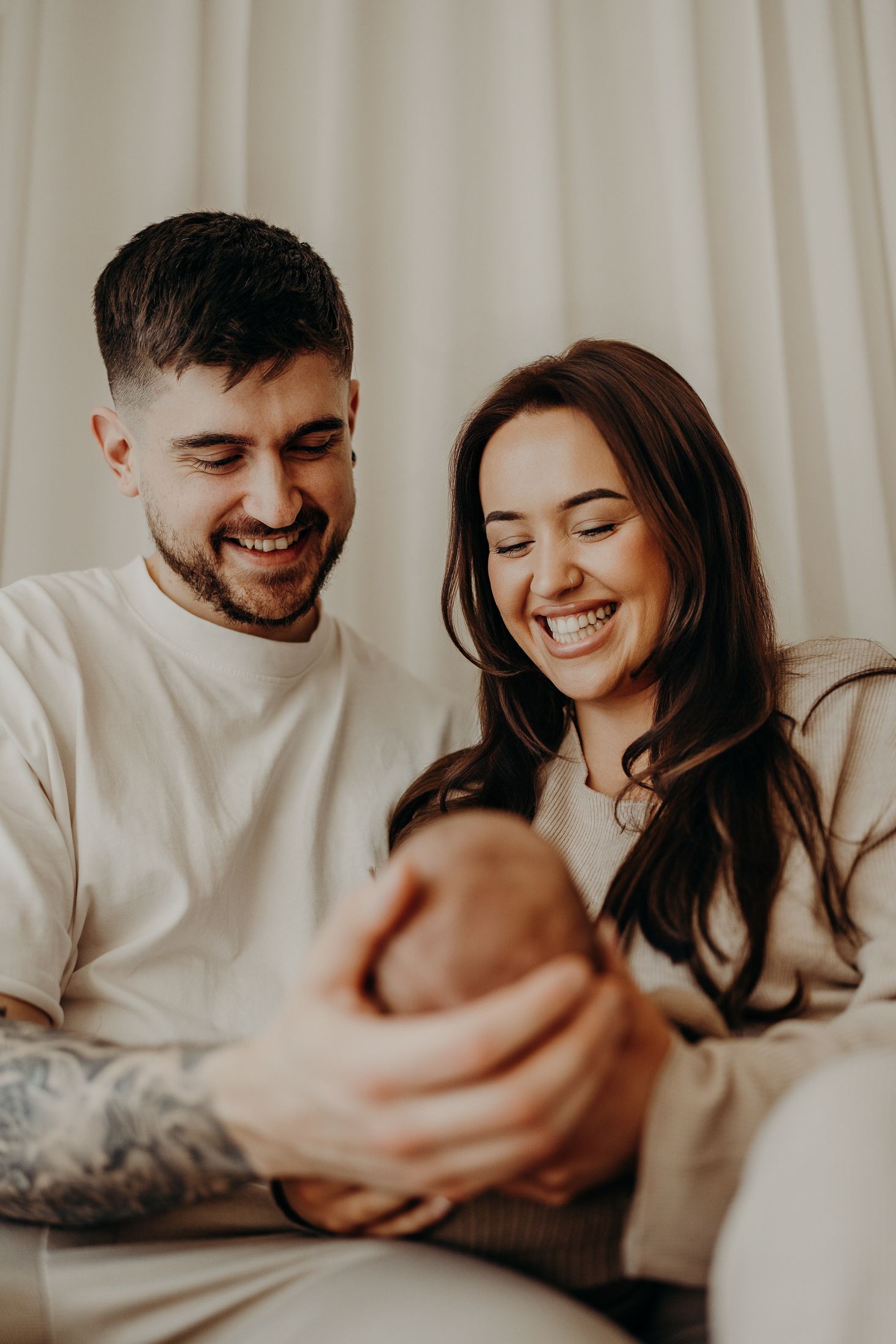 Happy parents cuddling their newborn during first days of parenting in natural lifestyle newborn session Dublin.