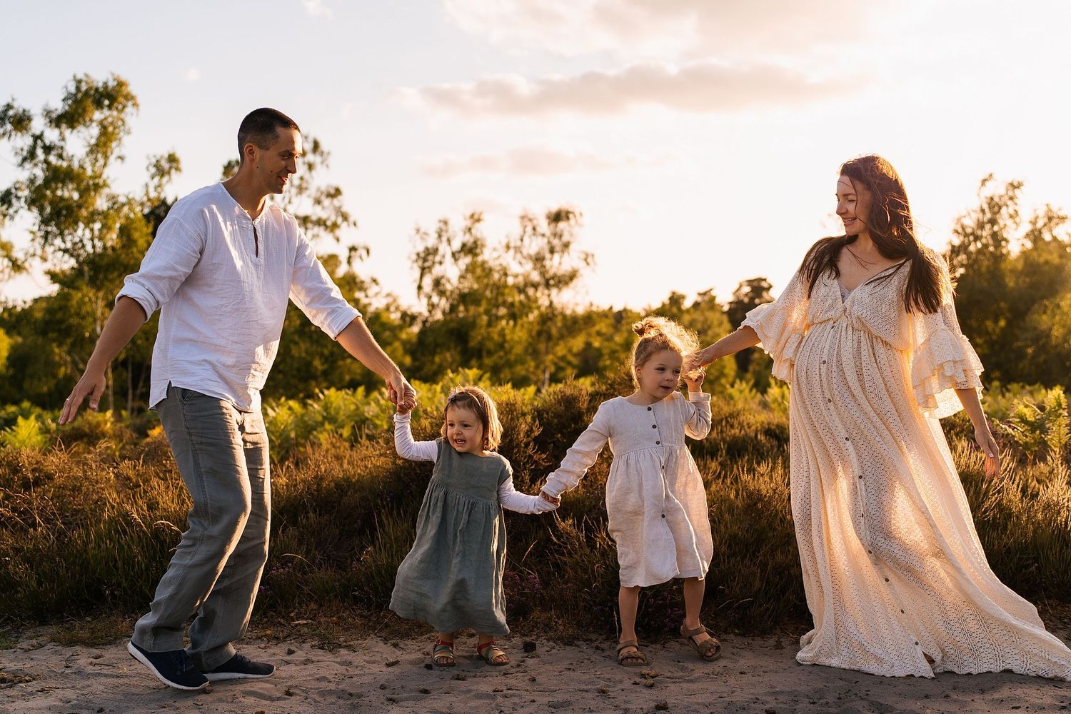 Family playing and dancing together outdoors during a sunset photoshoot.