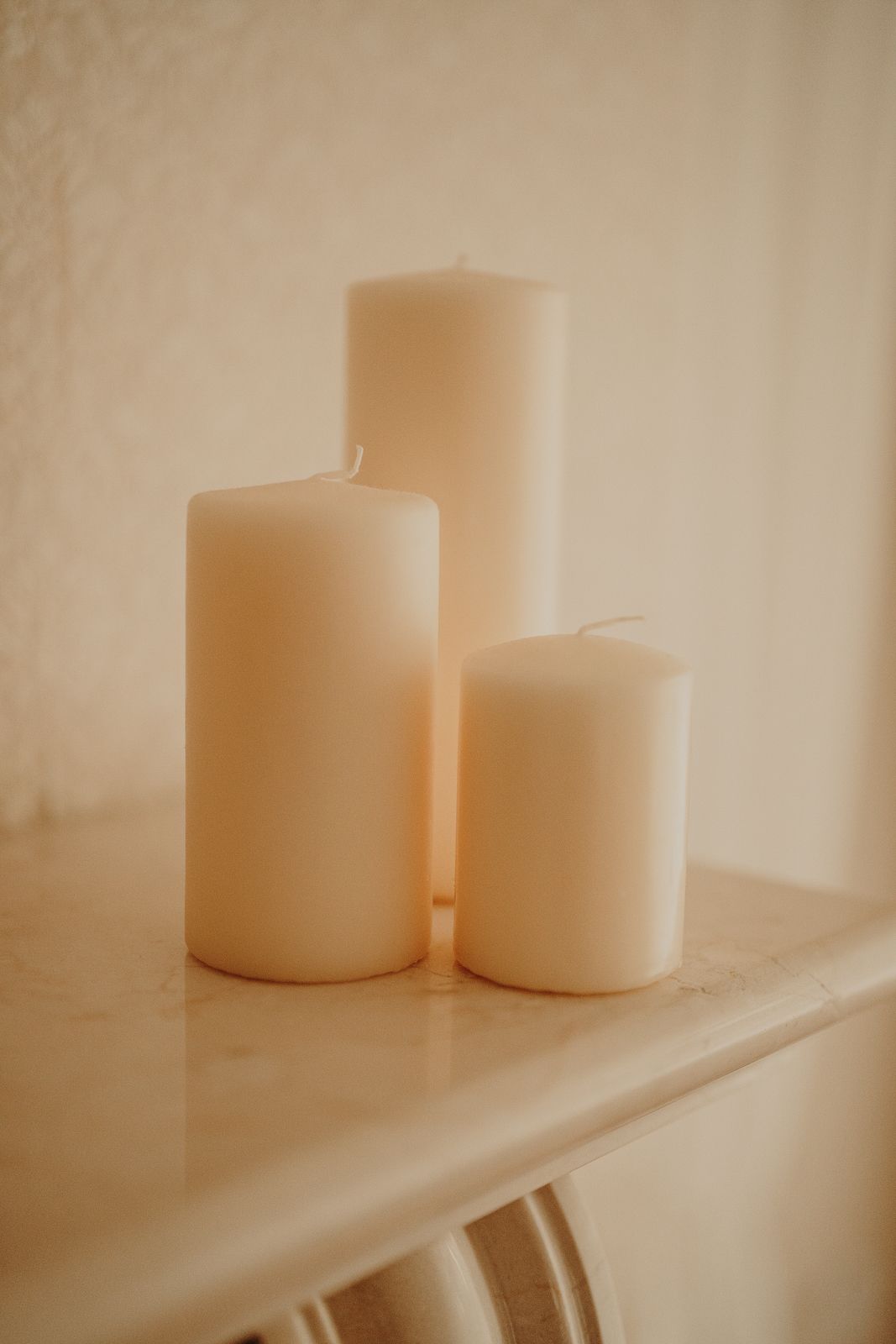 Minimalist arrangement of white pillar candles on a light surface.