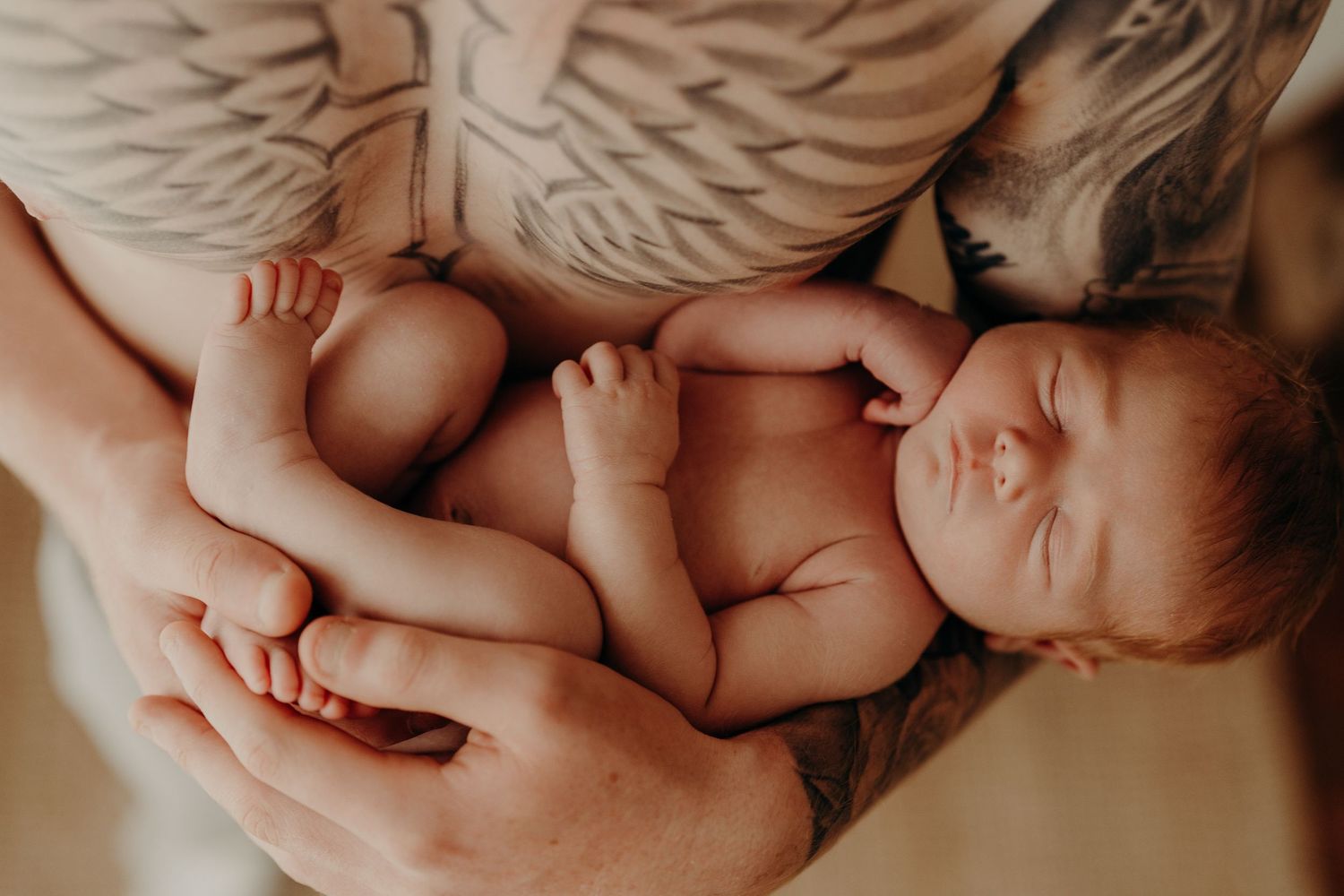 Newborn baby resting on soft angel wing prop during professional photo session.