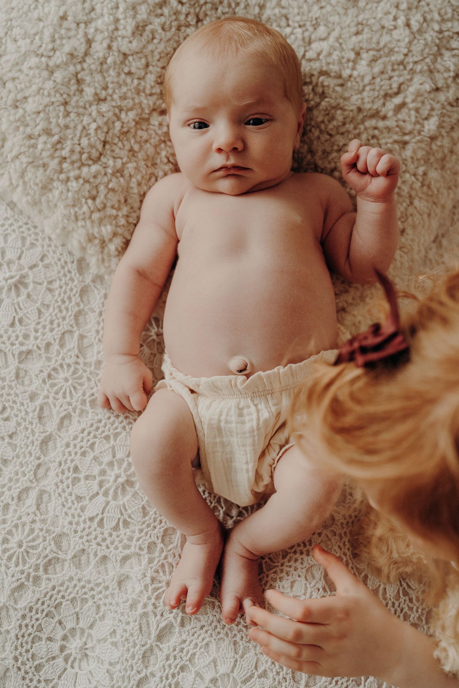Overhead view of sleeping baby on textured cream blanket during photo session.