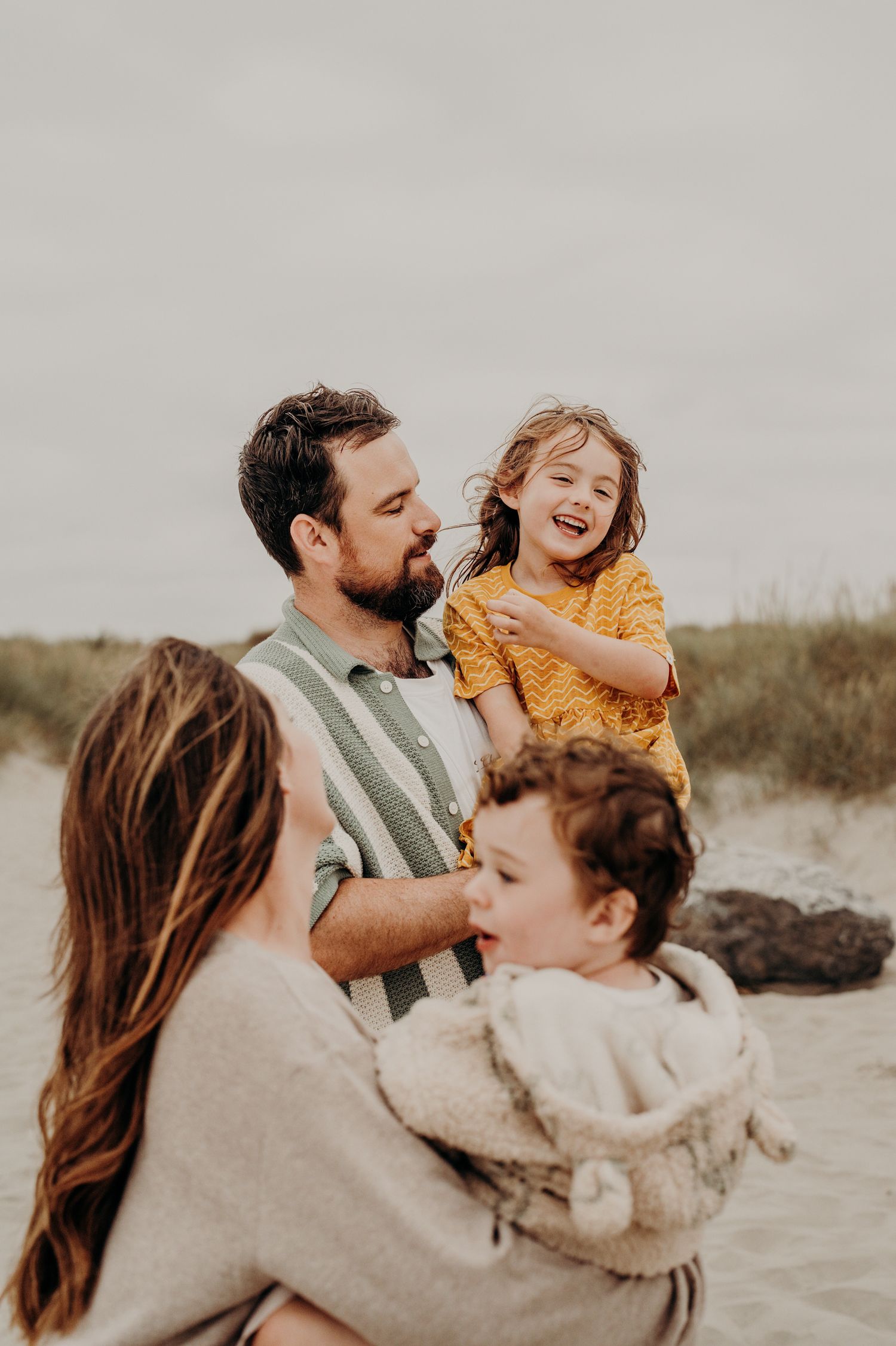 Warm family moments shared on a beach with natural golden light.