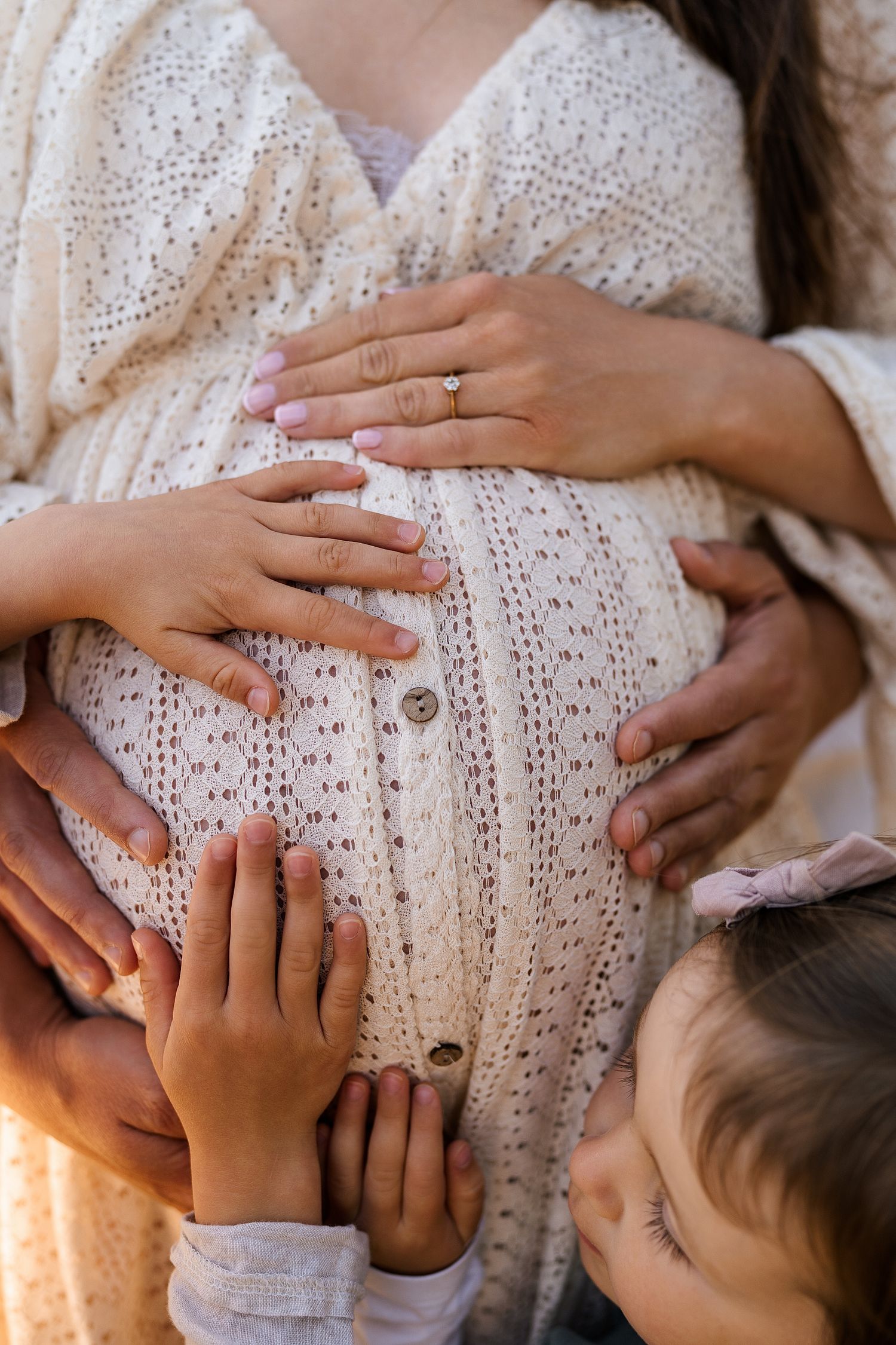 Intimate family maternity photos with hands lovingly placed on the baby bump.