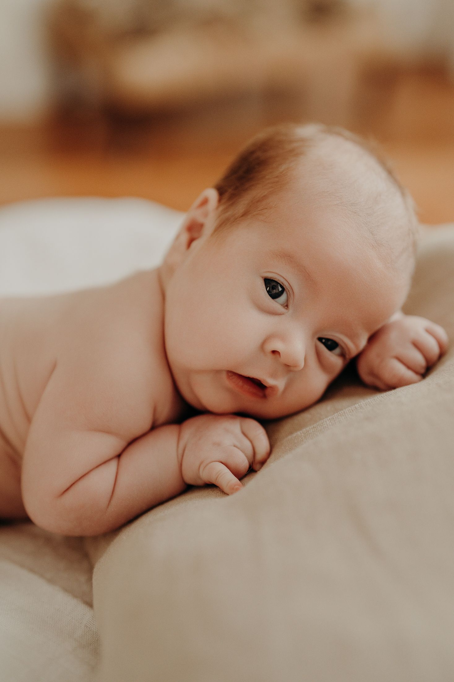 A tiny newborn baby rests on soft pillow, natural newborn session Dublin.