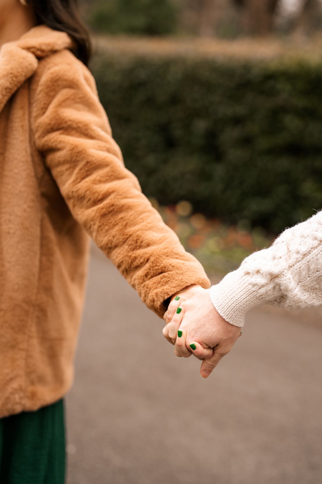 Two people's hands are clasped together while wearing warm coats, suggesting a close relationship.
