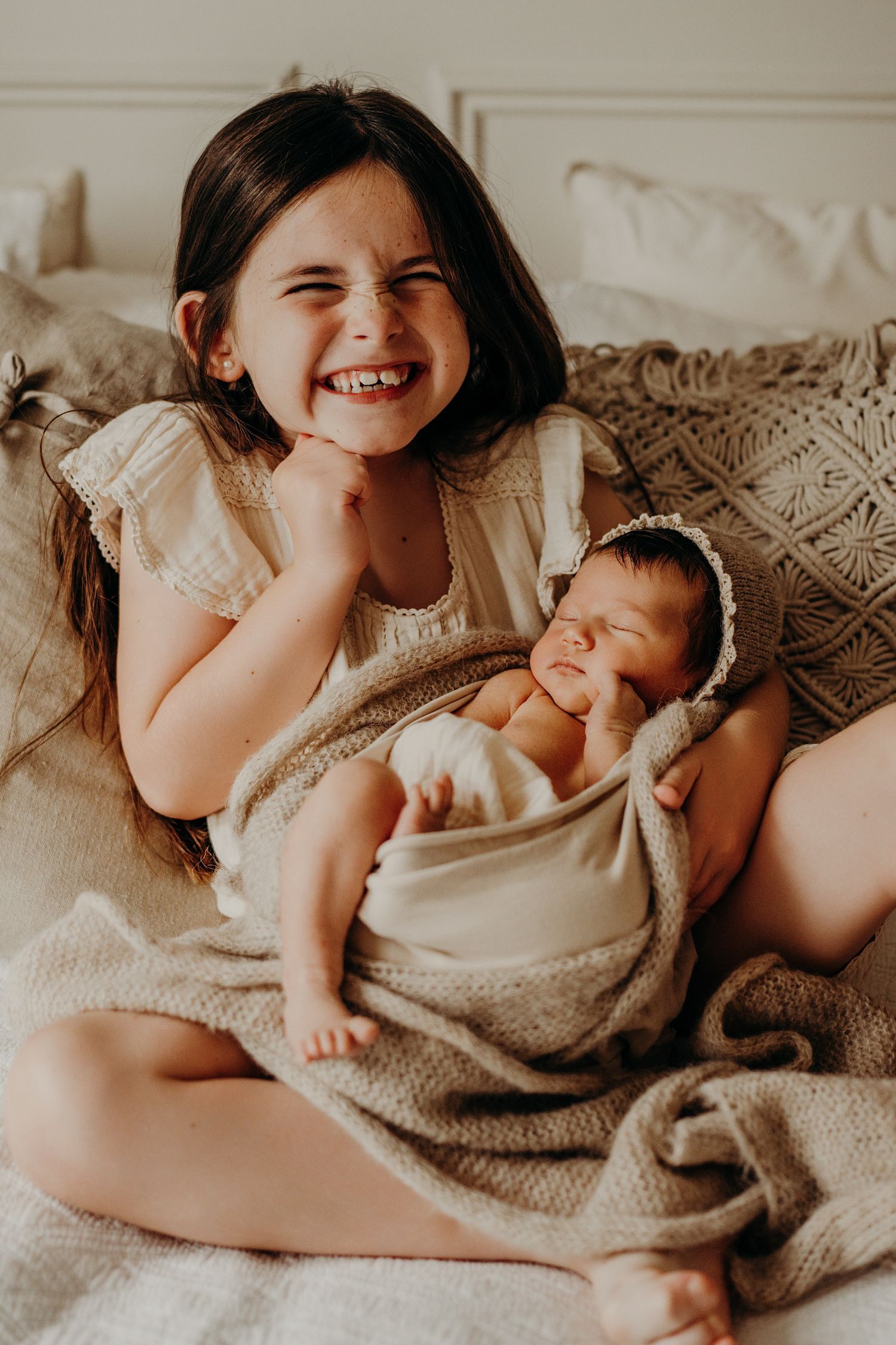 Sweet moment of siblings bonding on soft beige bedding.