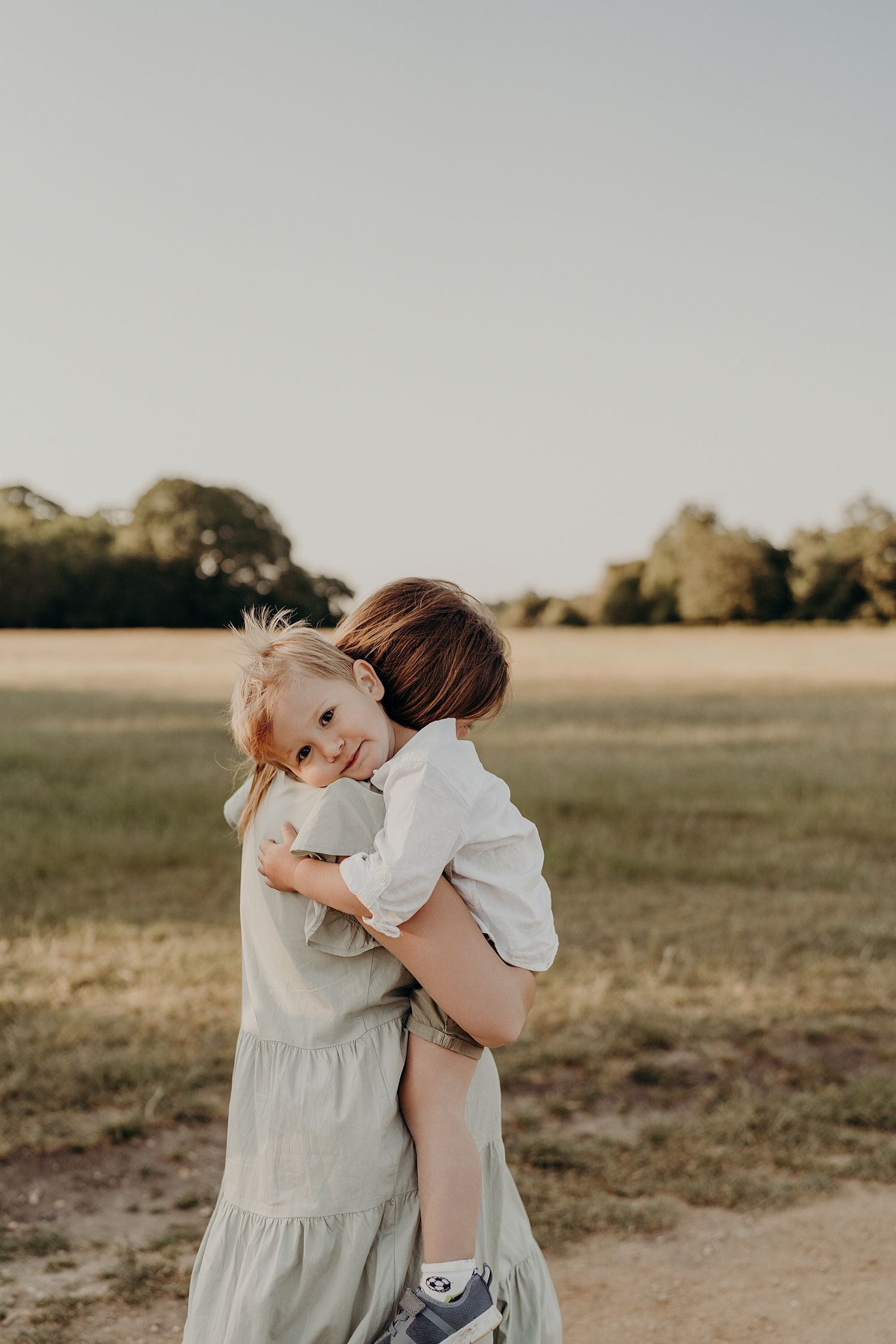 Tender embrace between two people in soft spring light on an open field.