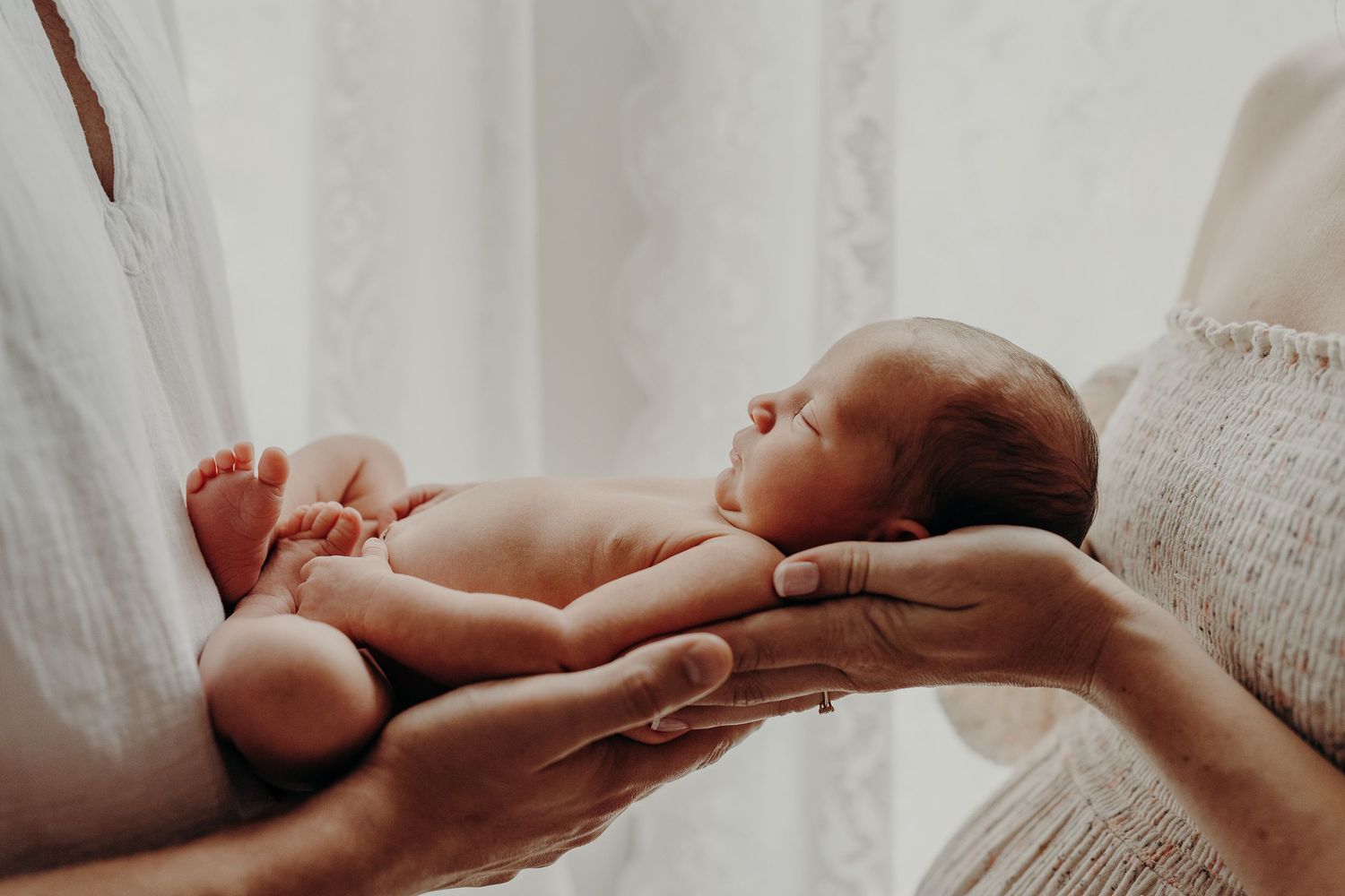 Close-up details of tiny newborn hands and fingers during intimate photo session.
