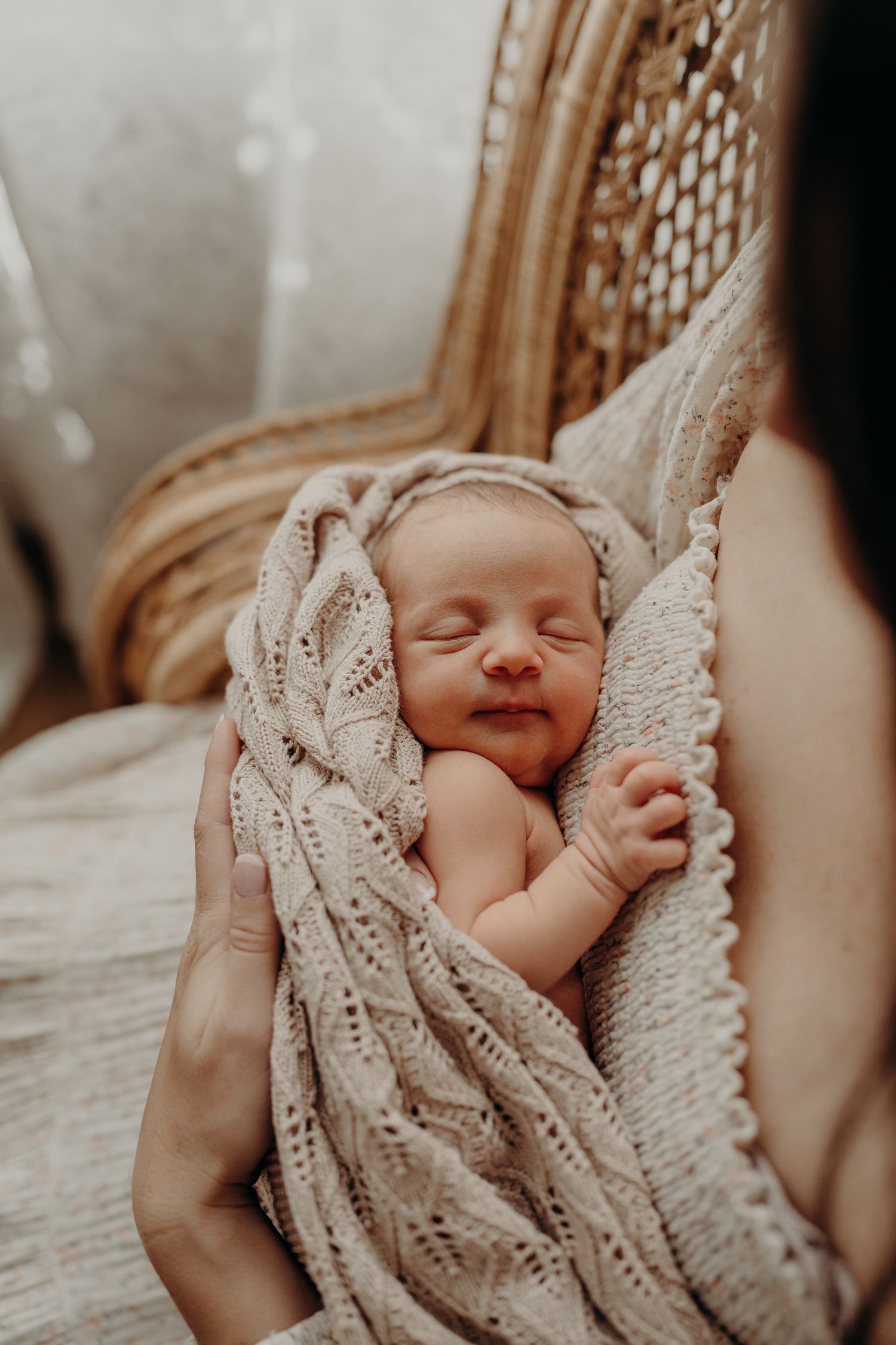 Sleeping newborn wrapped in delicate white lace blanket.
