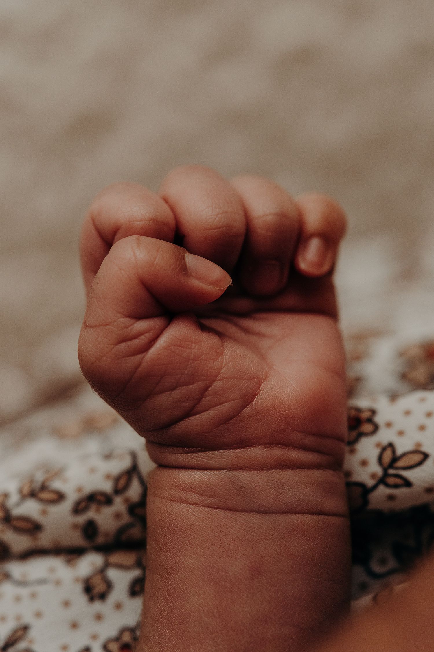 Close-up of tiny baby feet resting on floral patterned fabric.