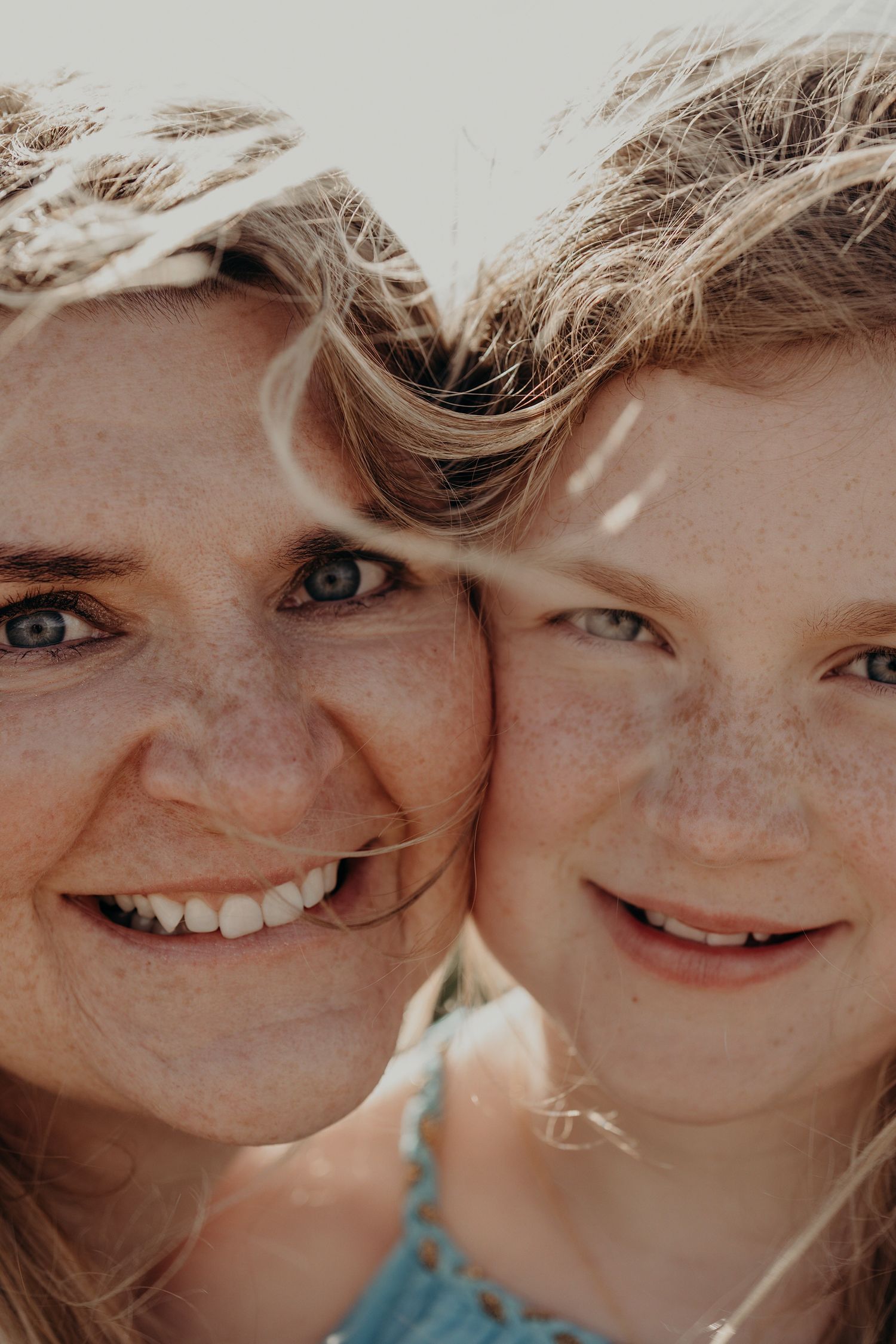 Close up portrait of smiling faces against bright background.