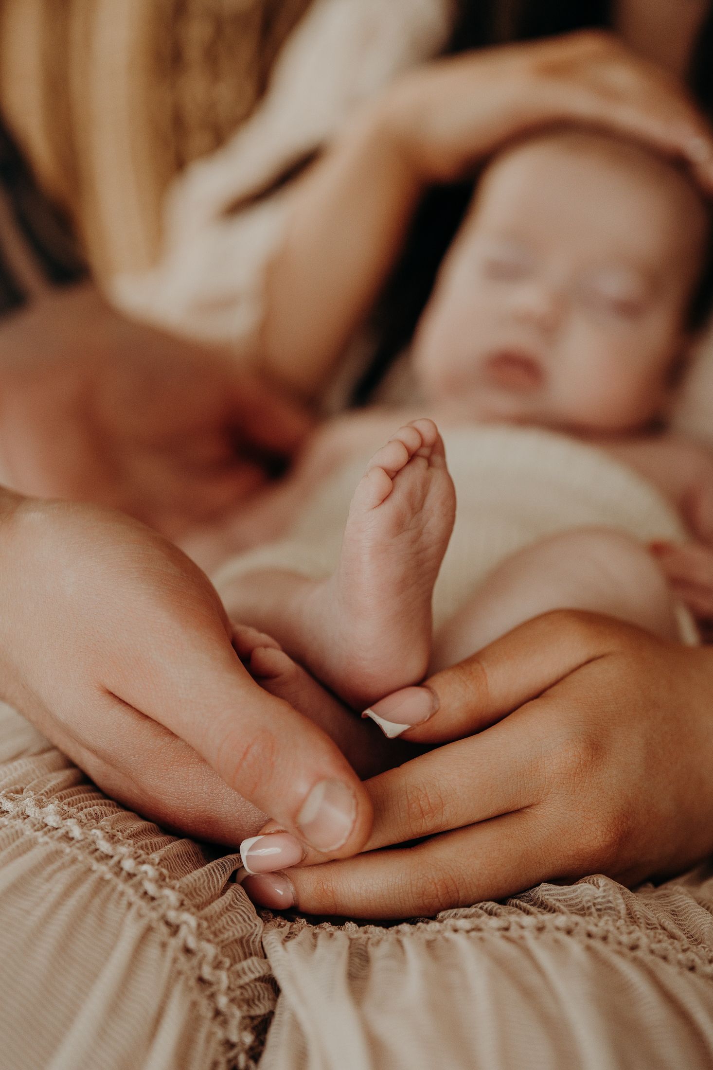 Close-up of tiny baby foot being gently held by parents, macro photography, natural newborn session dublin.