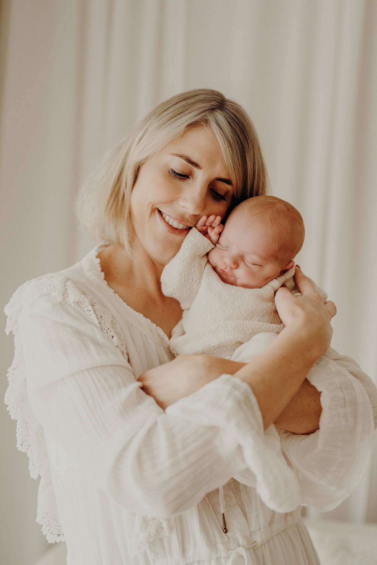 A tender moment captured in soft white tones showing gentle affection and connection.