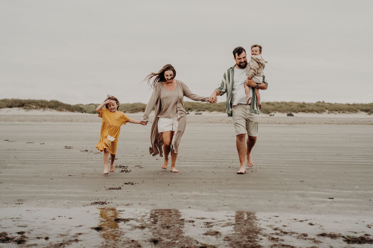 Candid shots of a family enjoying quality time together on an overcast beach.