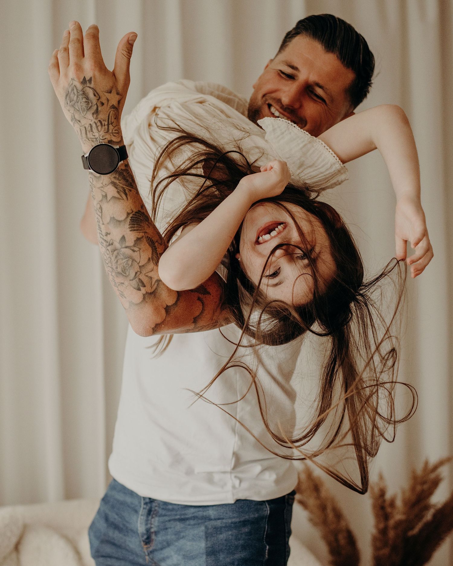 Couple sharing playful and intimate moments together against a light curtain background.