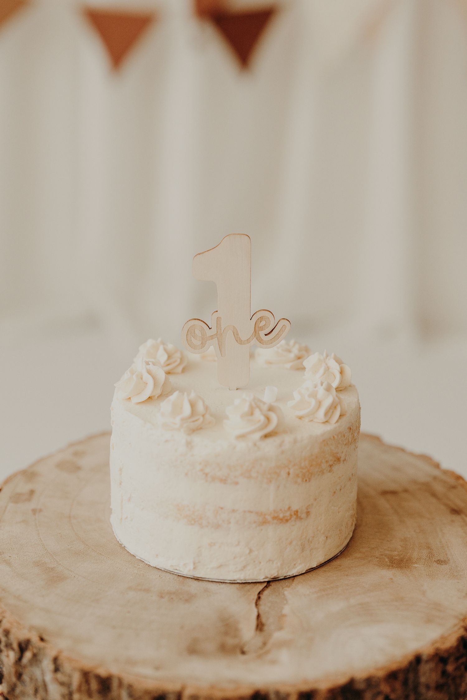 White frosted cake with delicate decorations on wooden cake stand.