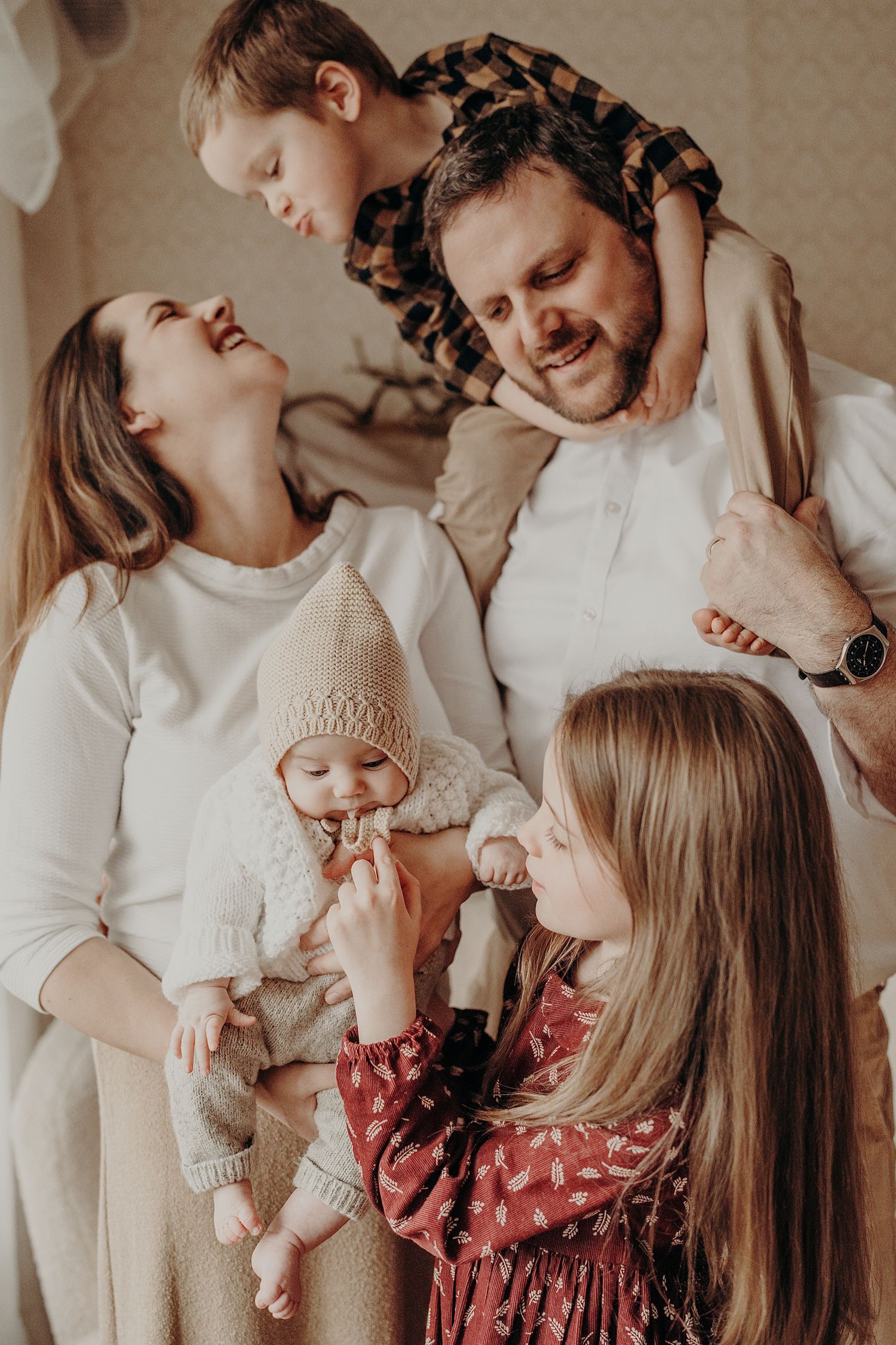 Indoor family lifestyle session with everyone wearing coordinated cream colored outfits.