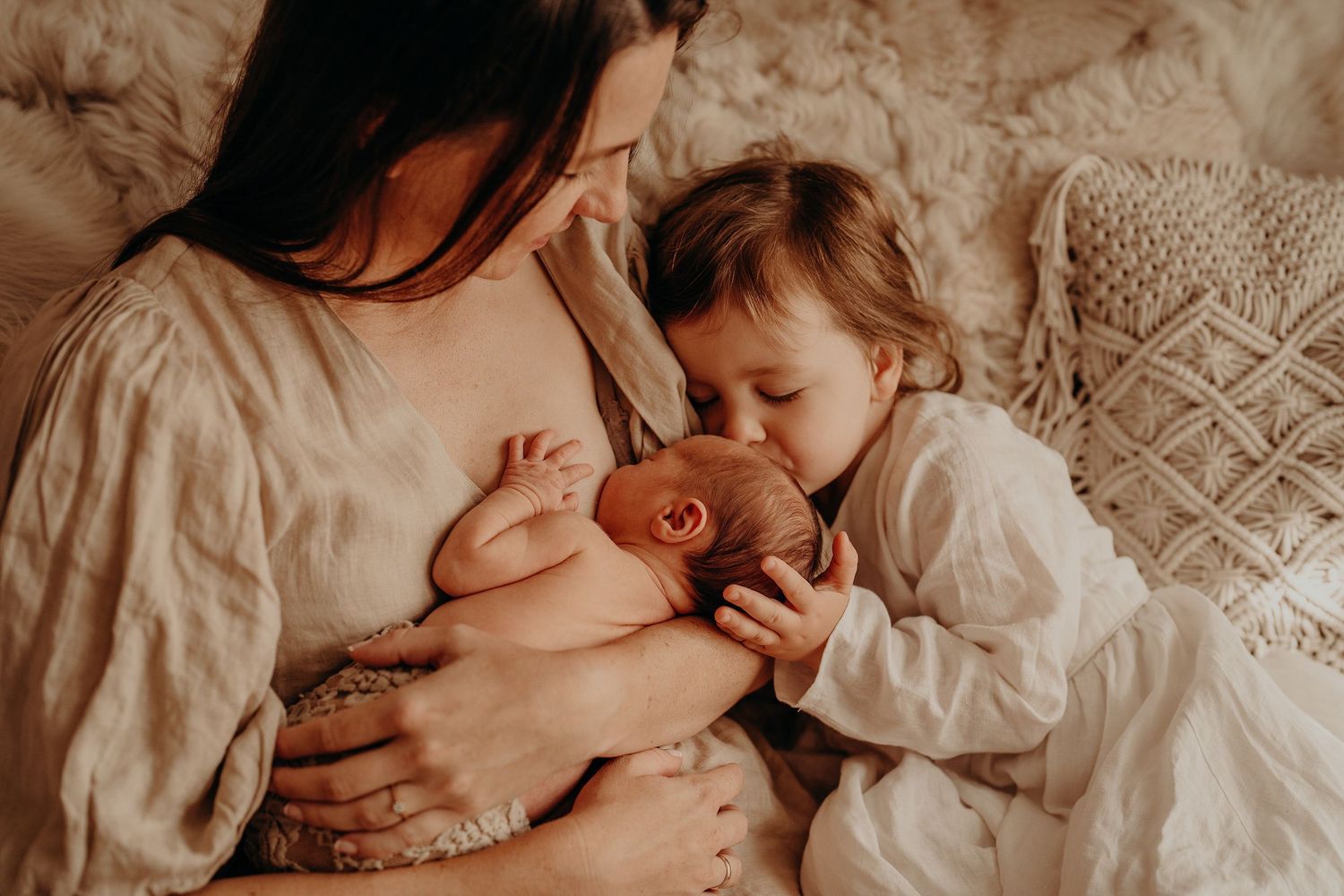 Intimate moments of parent and newborn baby in warm, muted tones.