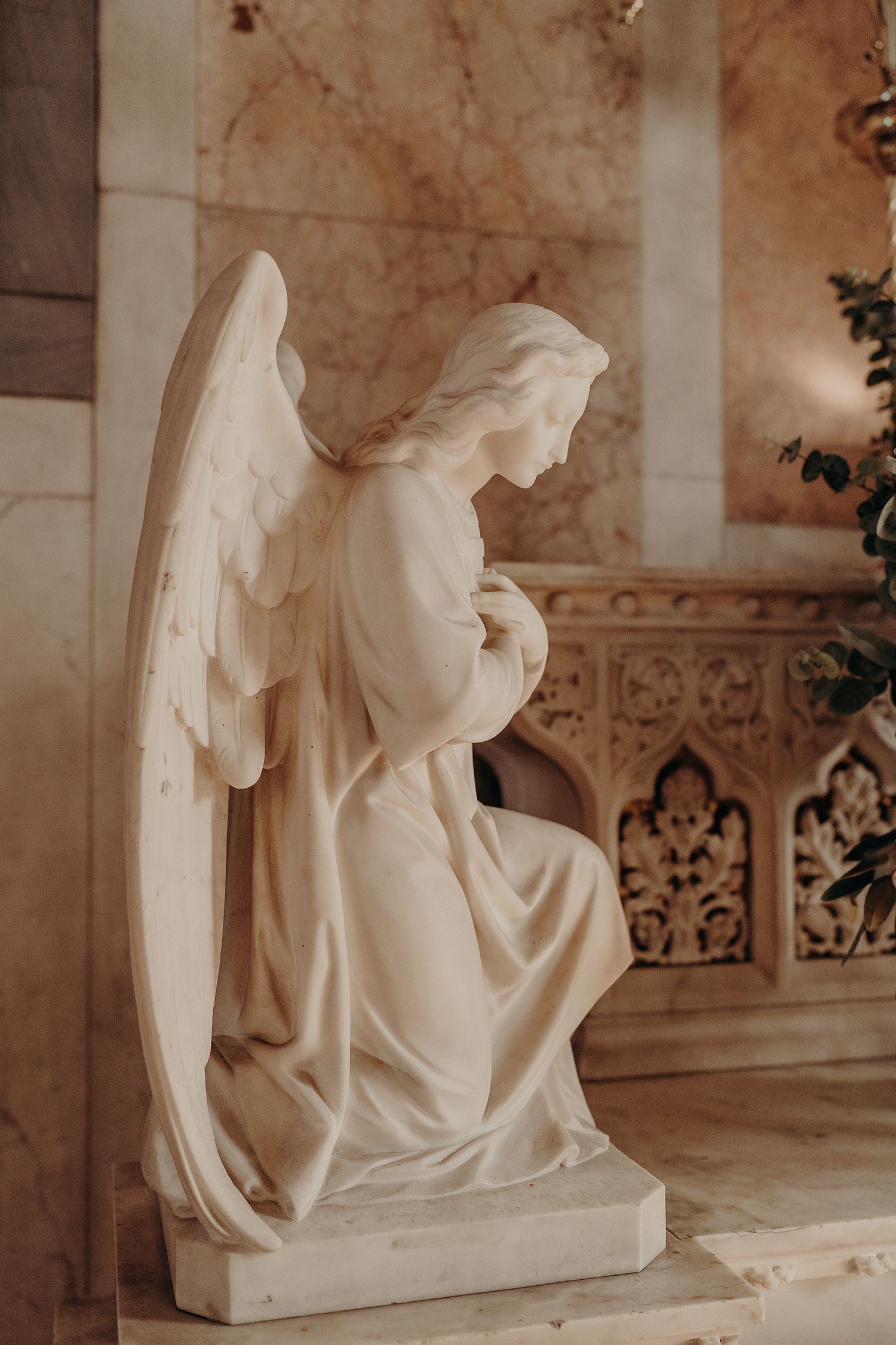 White marble religious sculpture depicting angelic figures in a classical architectural setting.
