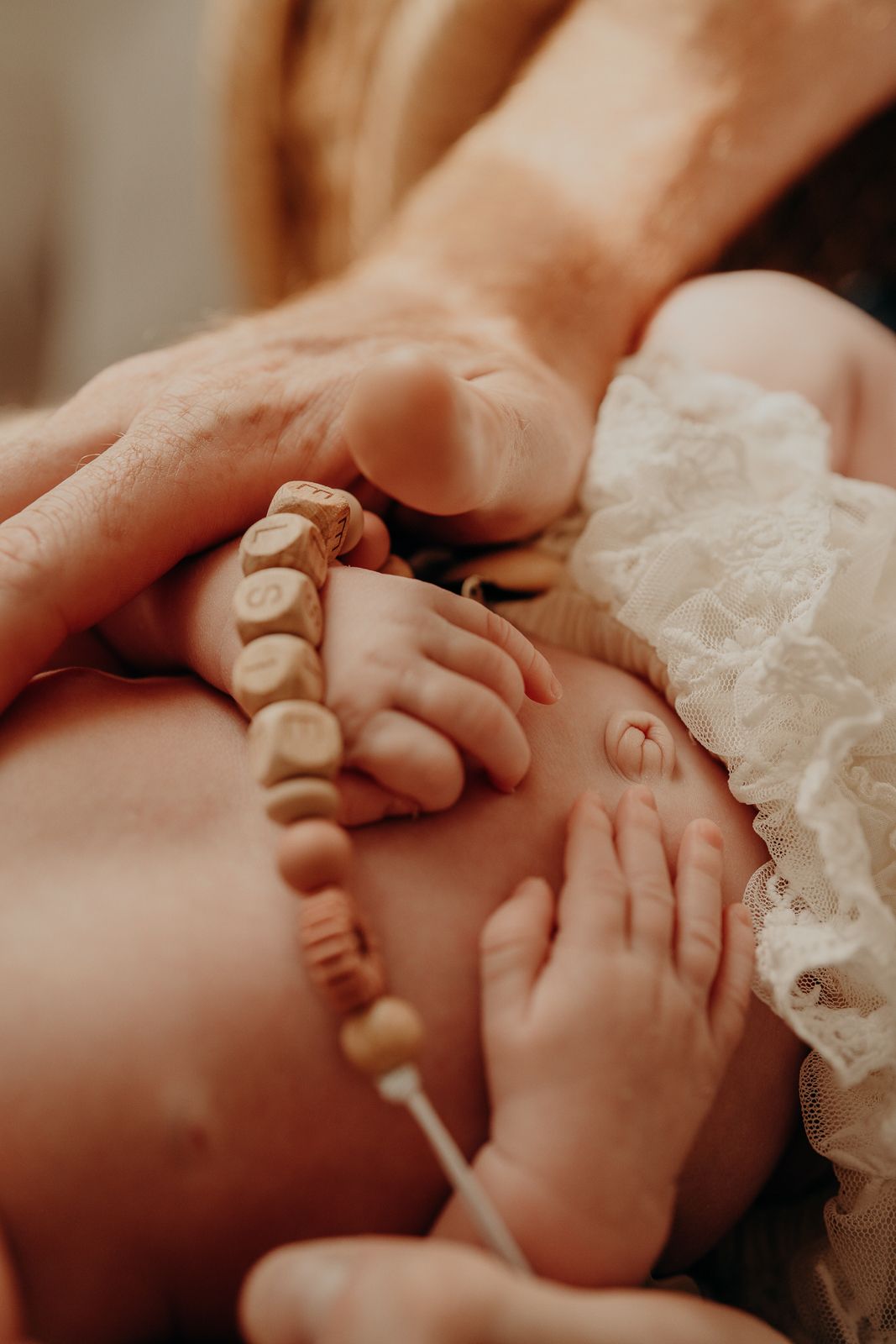 Delicate close-up of tiny baby feet with wooden beaded bracelet.