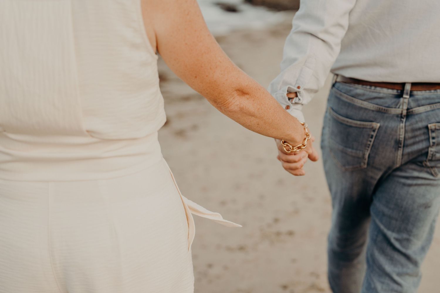 Cropped view of people's hands reaching toward each other outdoors.