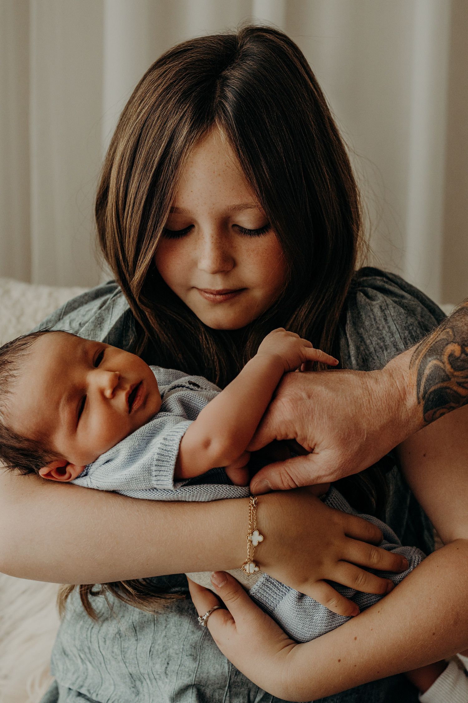Close-up series showing gentle interaction between sister and infant in muted tones.