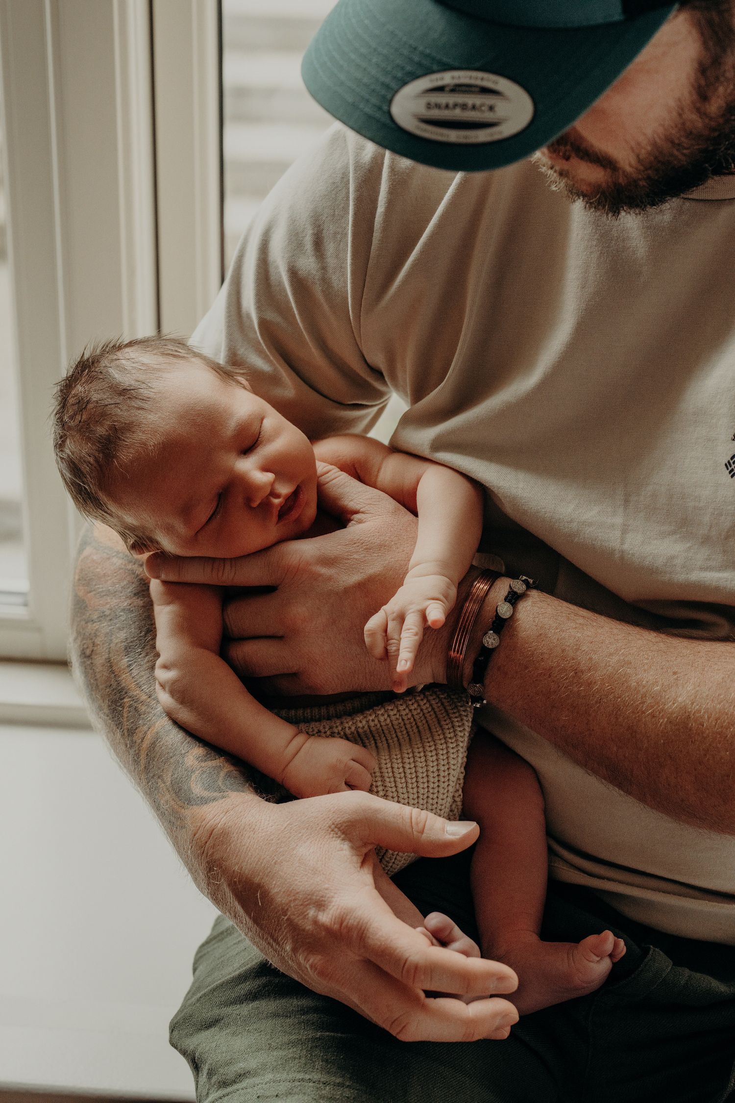 Parent holding and comforting newborn baby in gentle natural lighting.