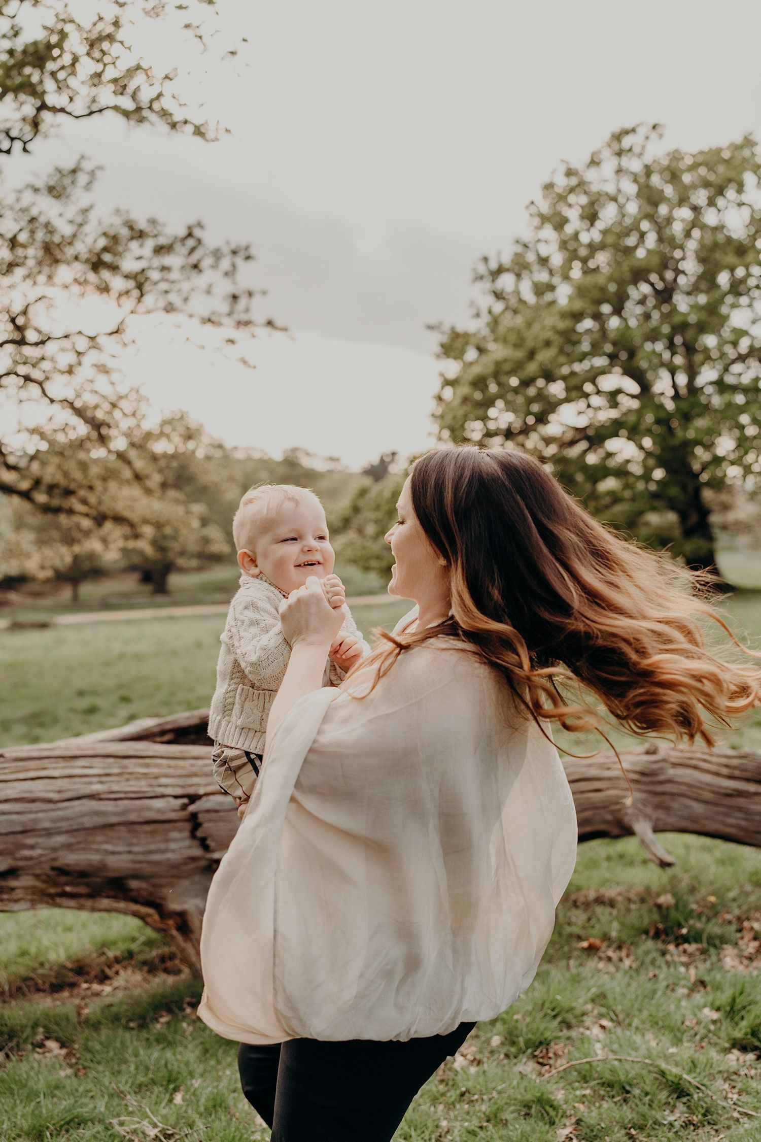 Mother and child playing together in a grassy park during golden hour.
