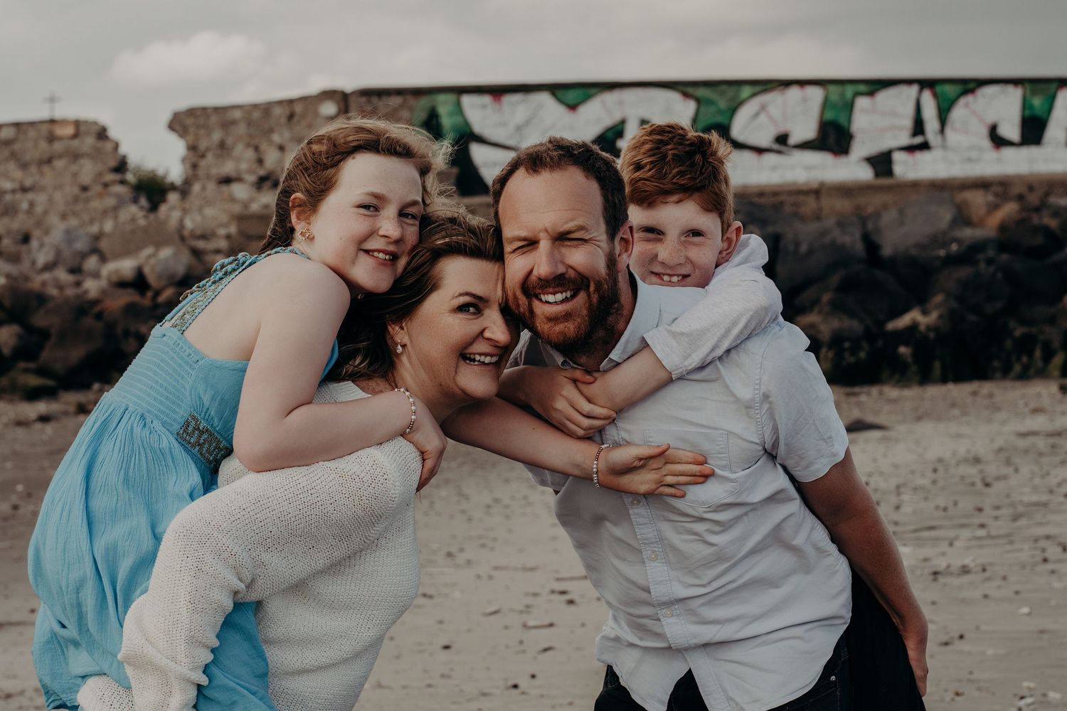 Natural candid moments of family affection captured on a coastal beach.