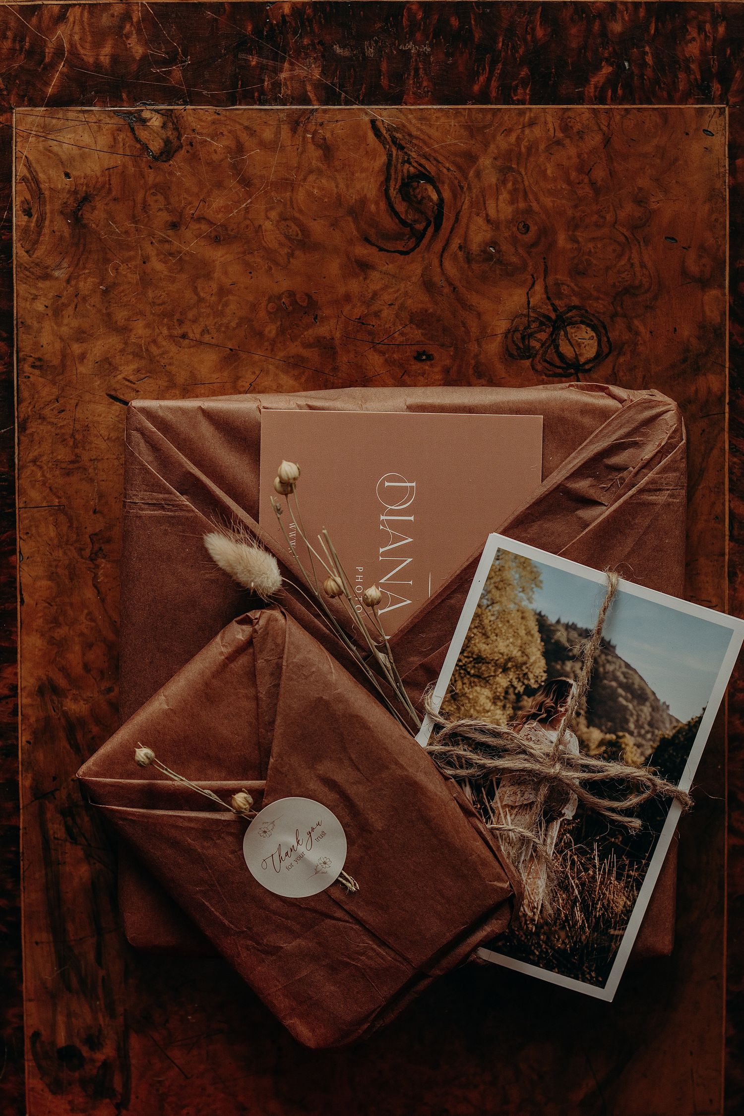 Vintage-style photography prints tied with twine on a dark wooden surface.