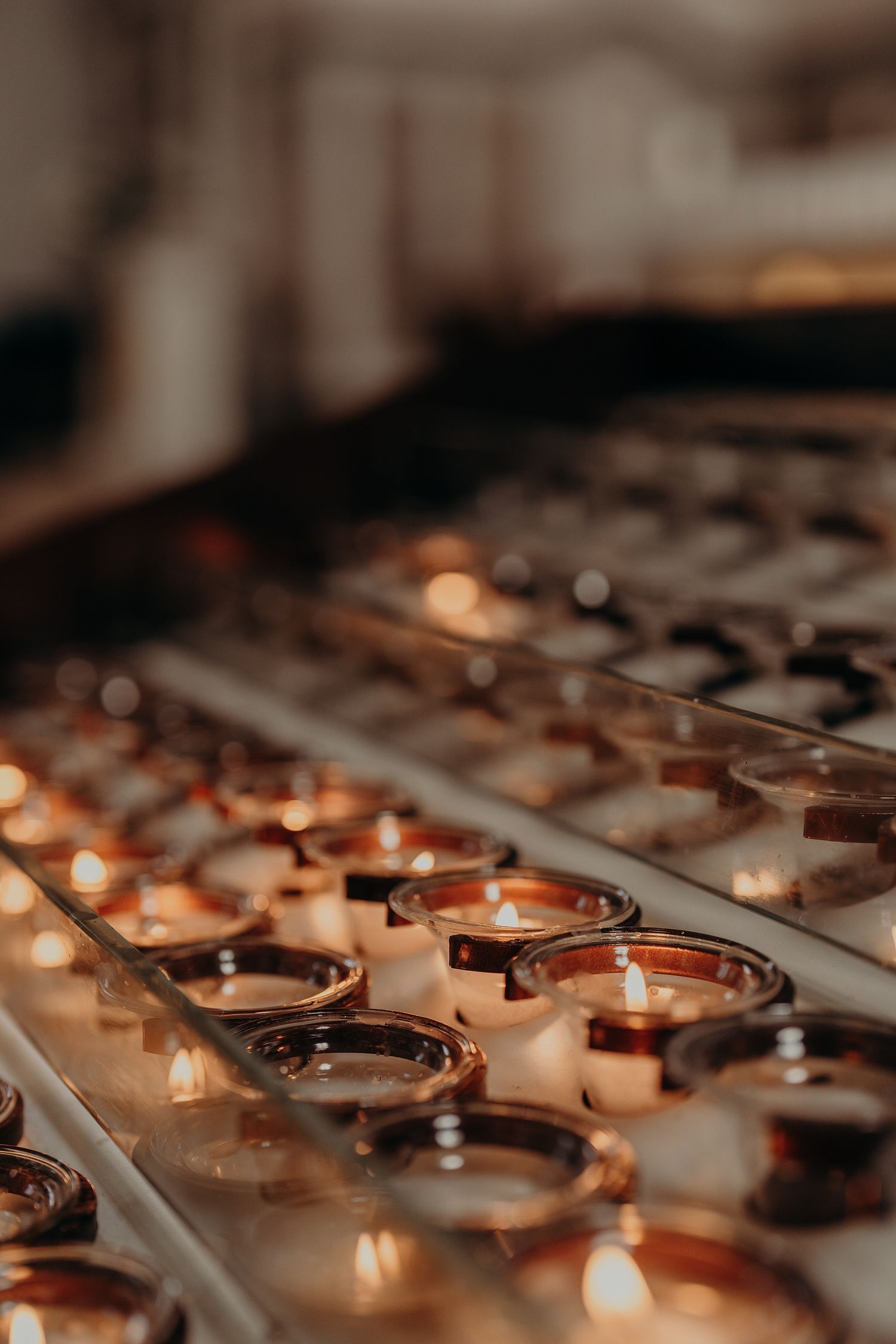 Rows of glowing votive candles creating a warm, spiritual atmosphere.