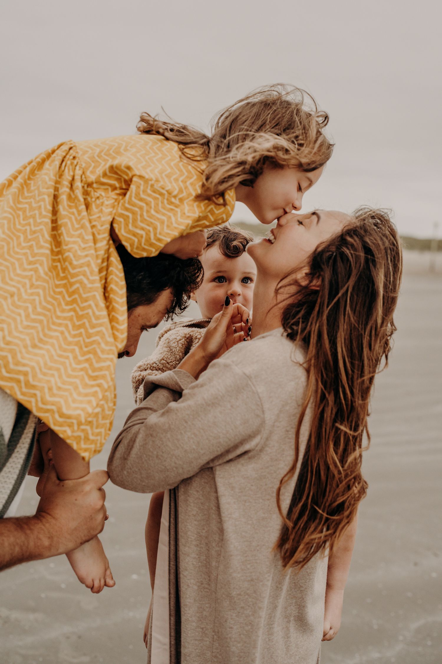 Joyful family moments shared between parents and child in warm natural tones on the beach.