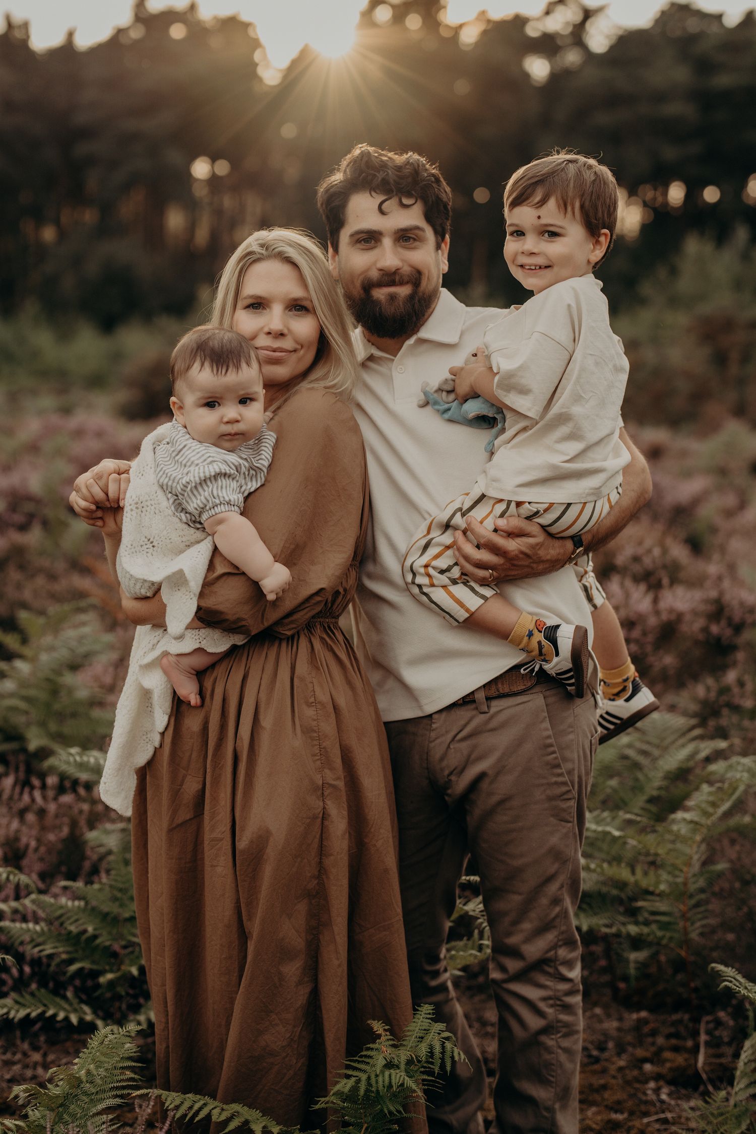 Outdoor family portrait session in earth tones against sunset lighting and natural foliage.