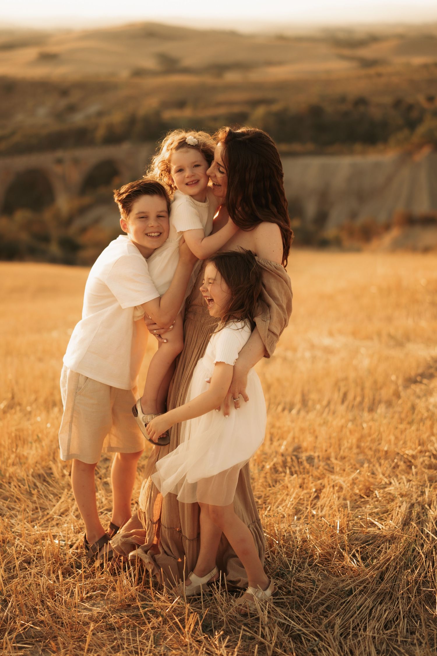 Family photoshoot in a golden wheat field during sunset with warm natural lighting. Photo by Ilara Masotti.